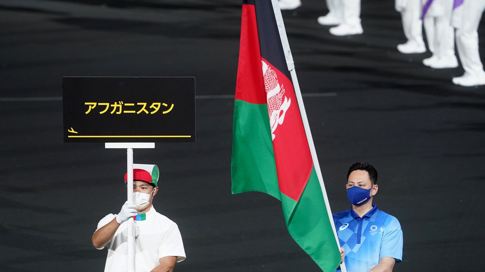 The flag of Afghanistan is presented by volunteers at the Paralympics.