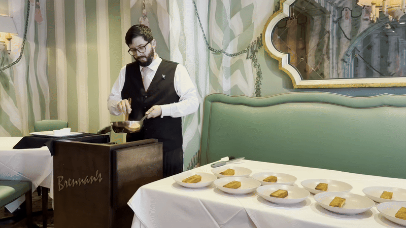 A man scrambles eggs at a station labeled Brennan's next to plates of toast.