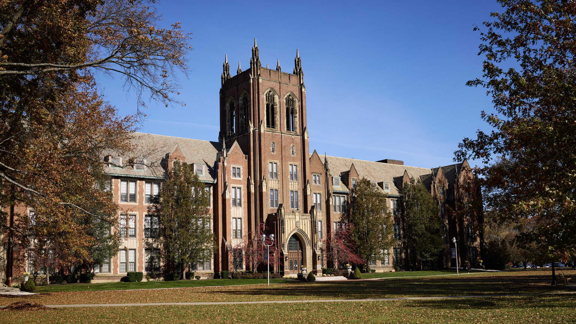 Red brick gothic building (college campus) with blue sky and autumn trees