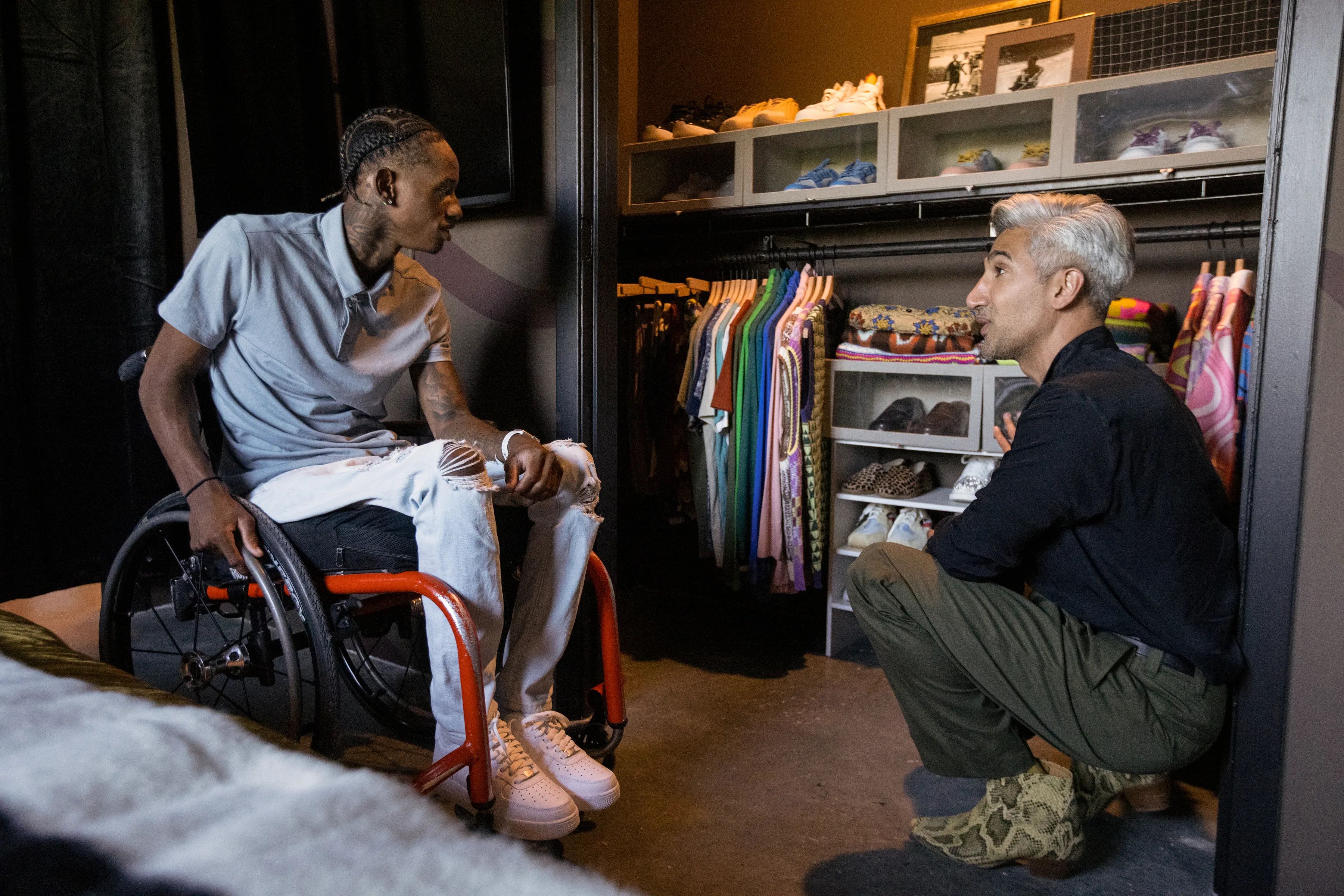 Photo shows Ray Walker talking with Tan France  in front of a closet.