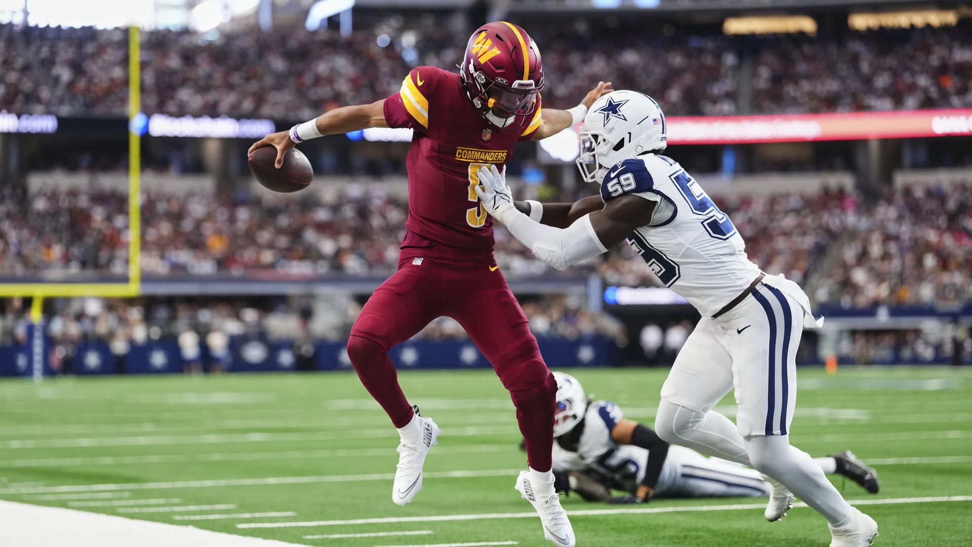 Quarter back Jayden Daniels tries to jump away from a tackle. 