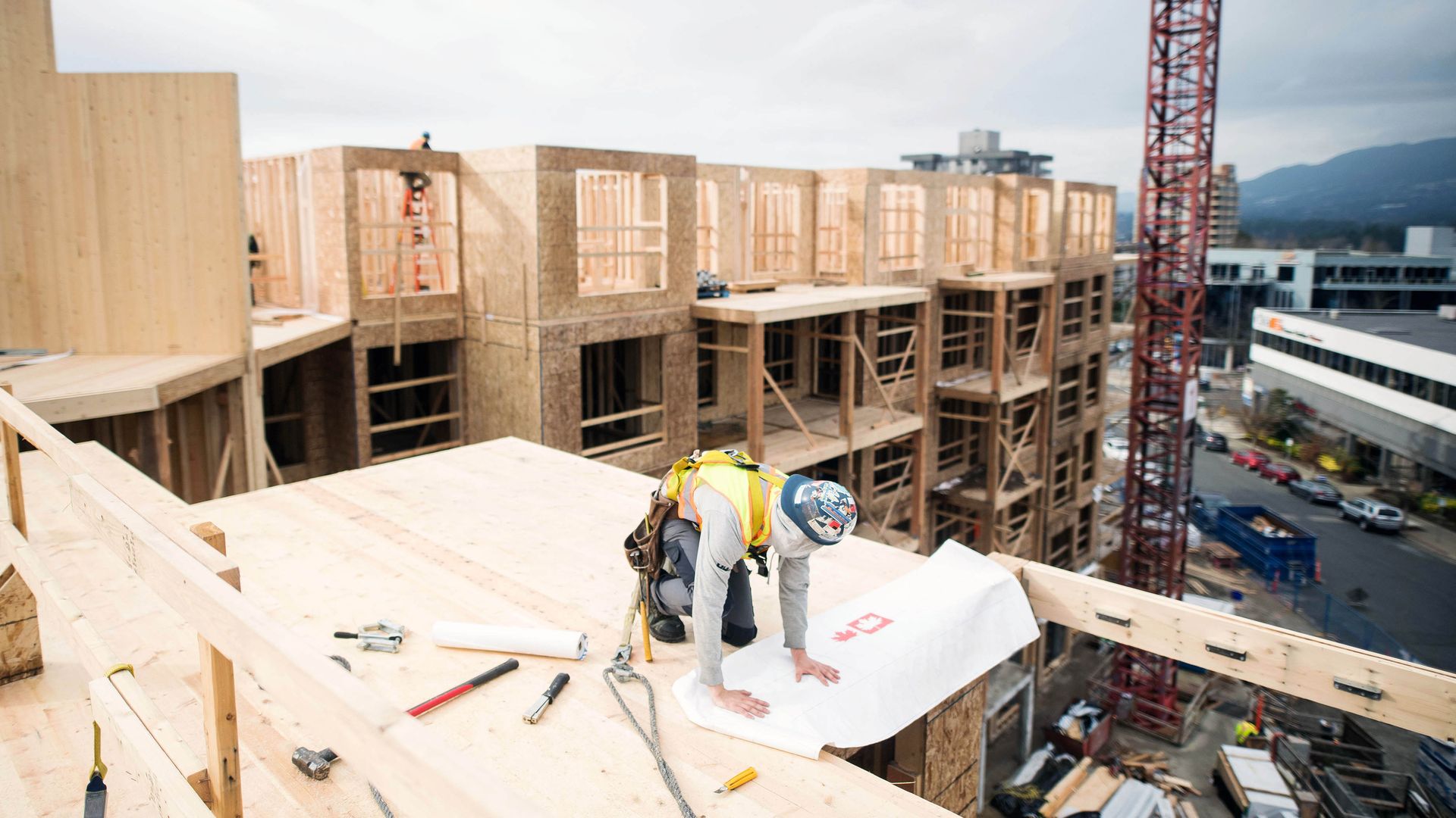 A worker on a construction site helps build a mass-timber high rise.