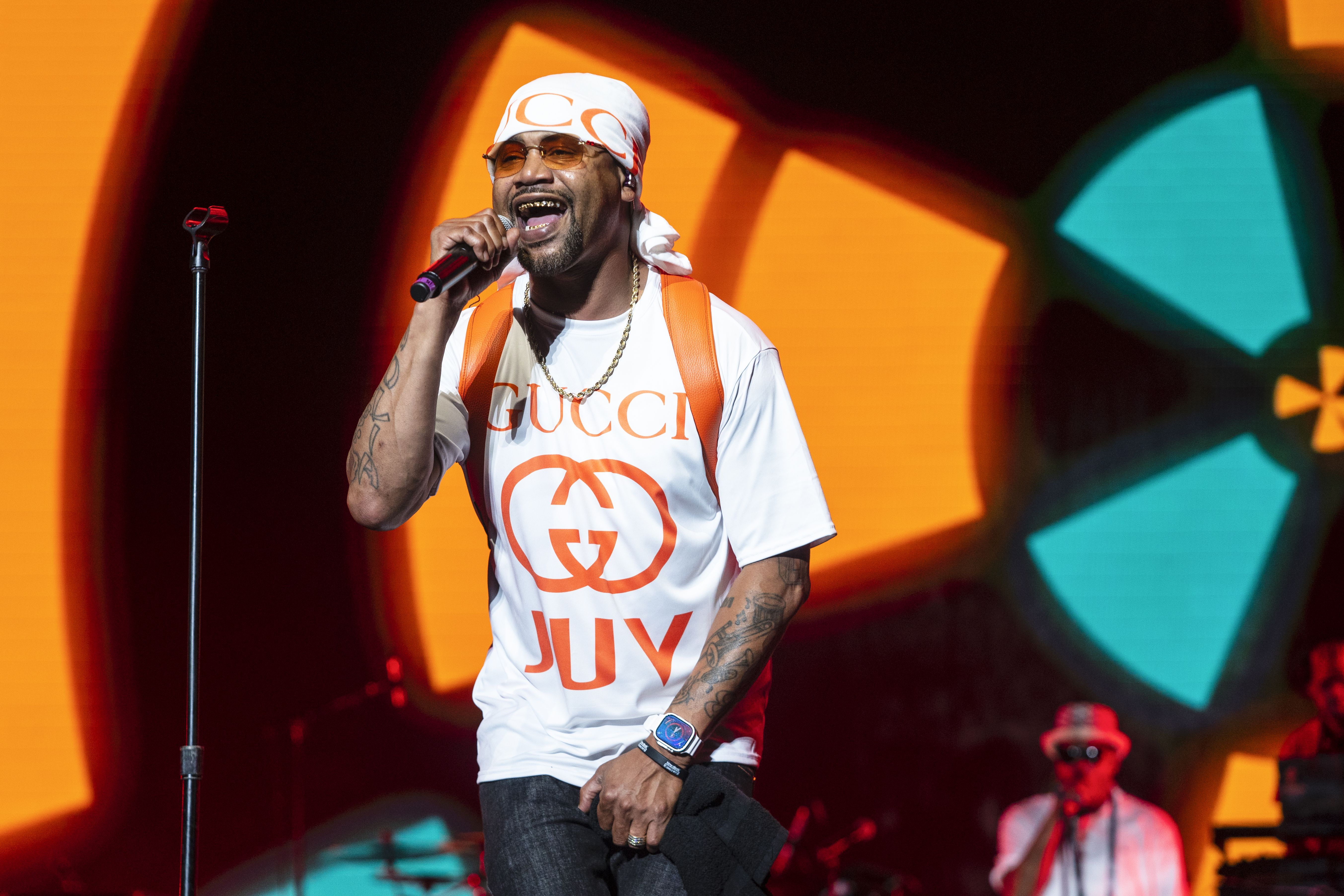 Photo shows Juvenile holding a mic while he performs on stage at Essence