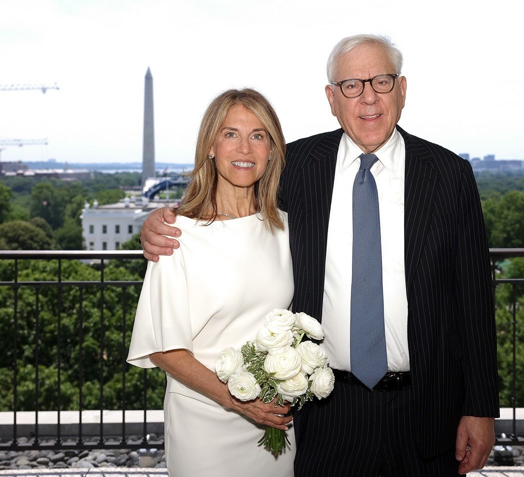 Bride and groom pose on a balcony with a view of the Washington Monument