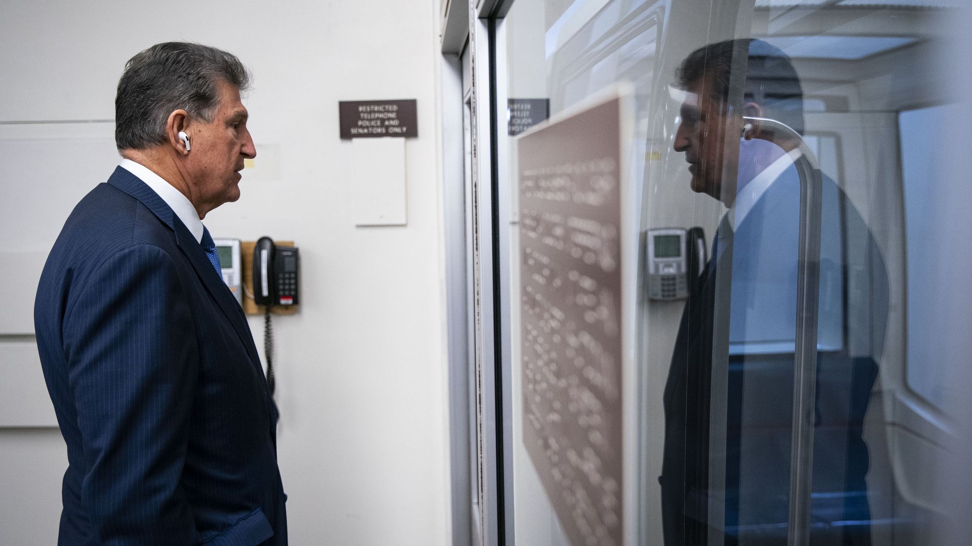 Sen. Joe Manchin and his reflection are seen as he speaks in a Senate subway car.