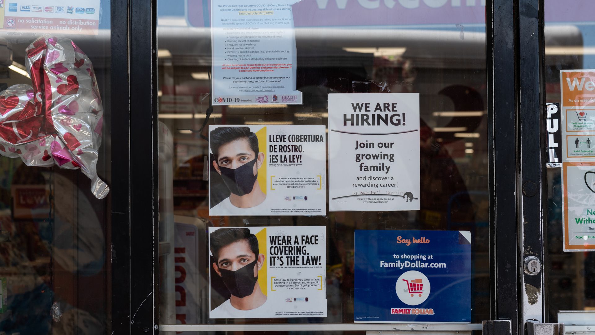 A "we are hiring" sign on a glass door