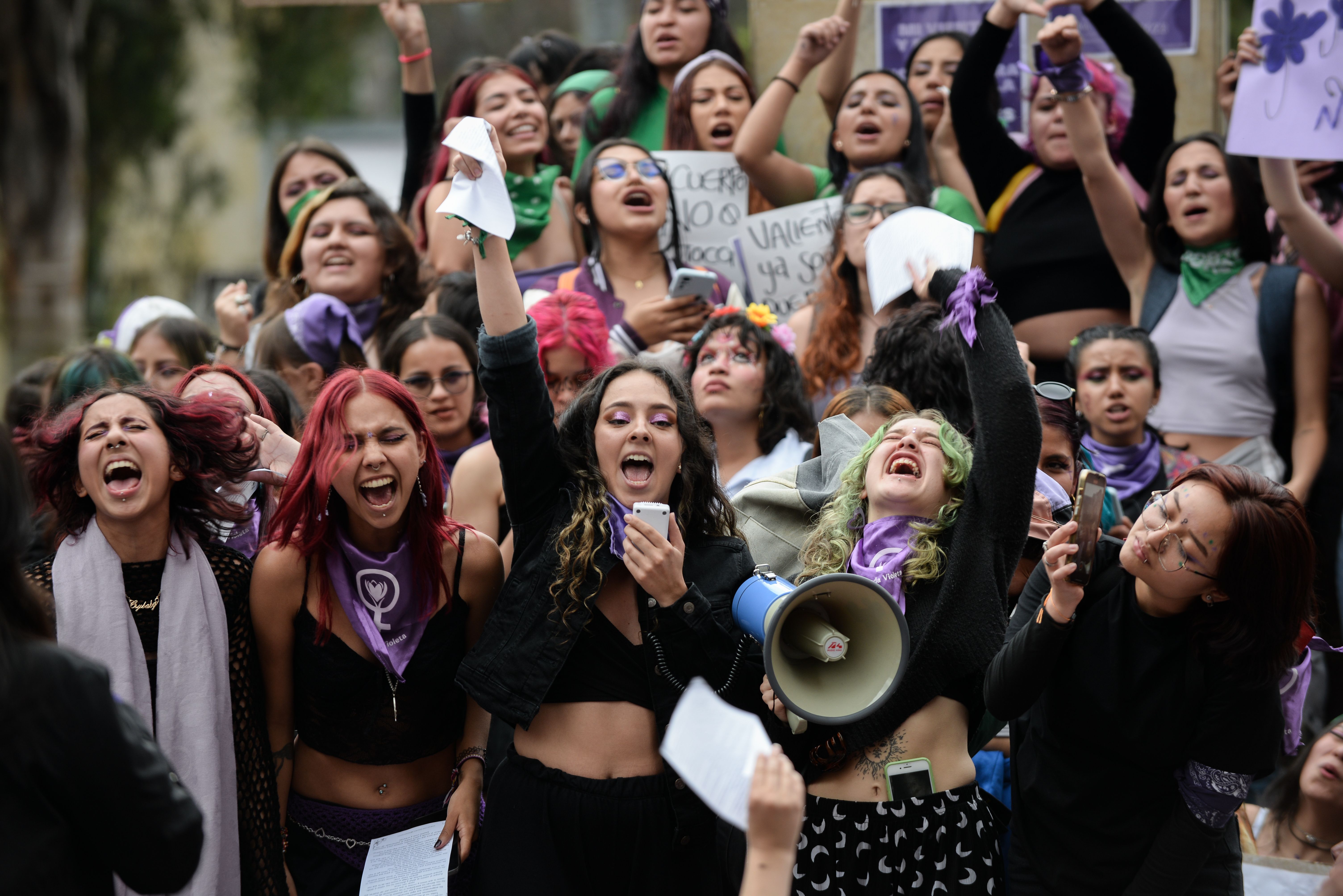 Demonstrators raise their arms in the air and yell during a protest for International Women's Day in Bogota, Colombia