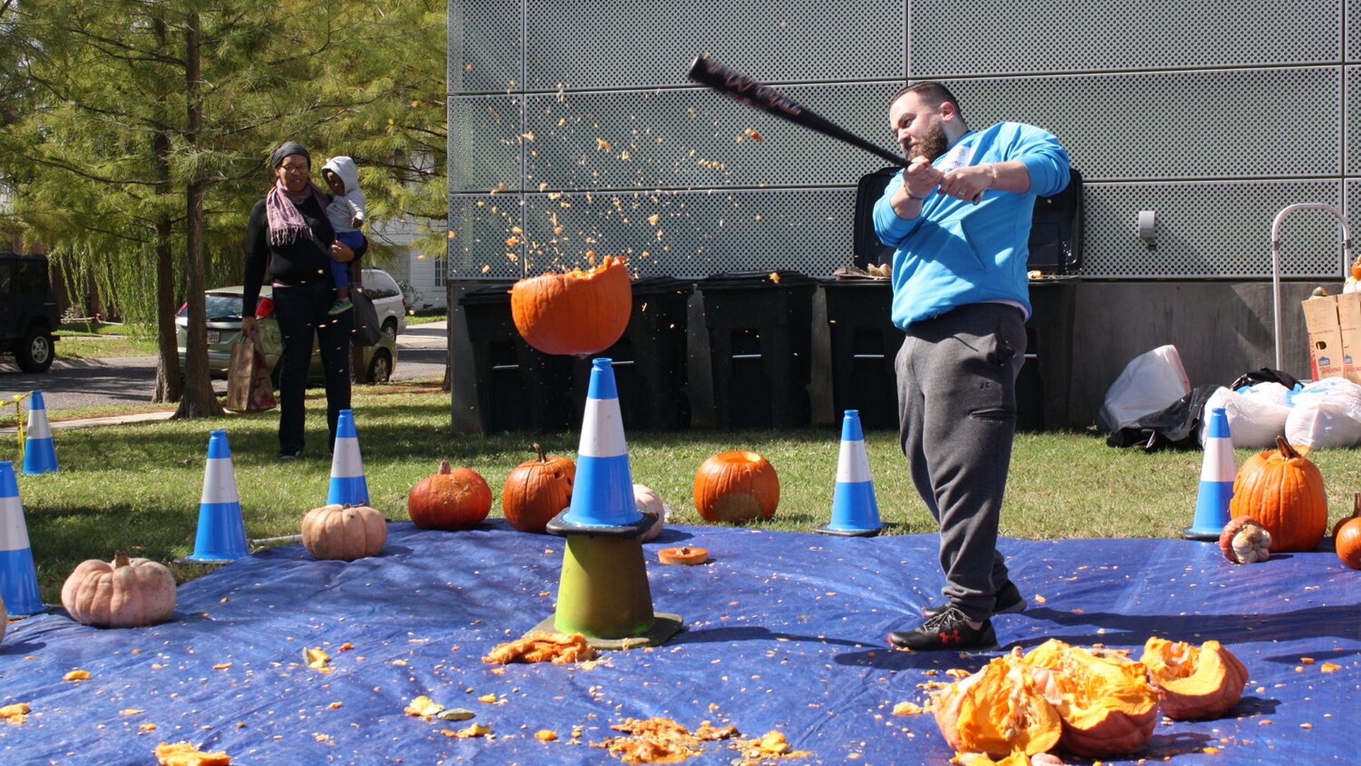 Photo shows a man smashing a pumpkin with a baseball bat.