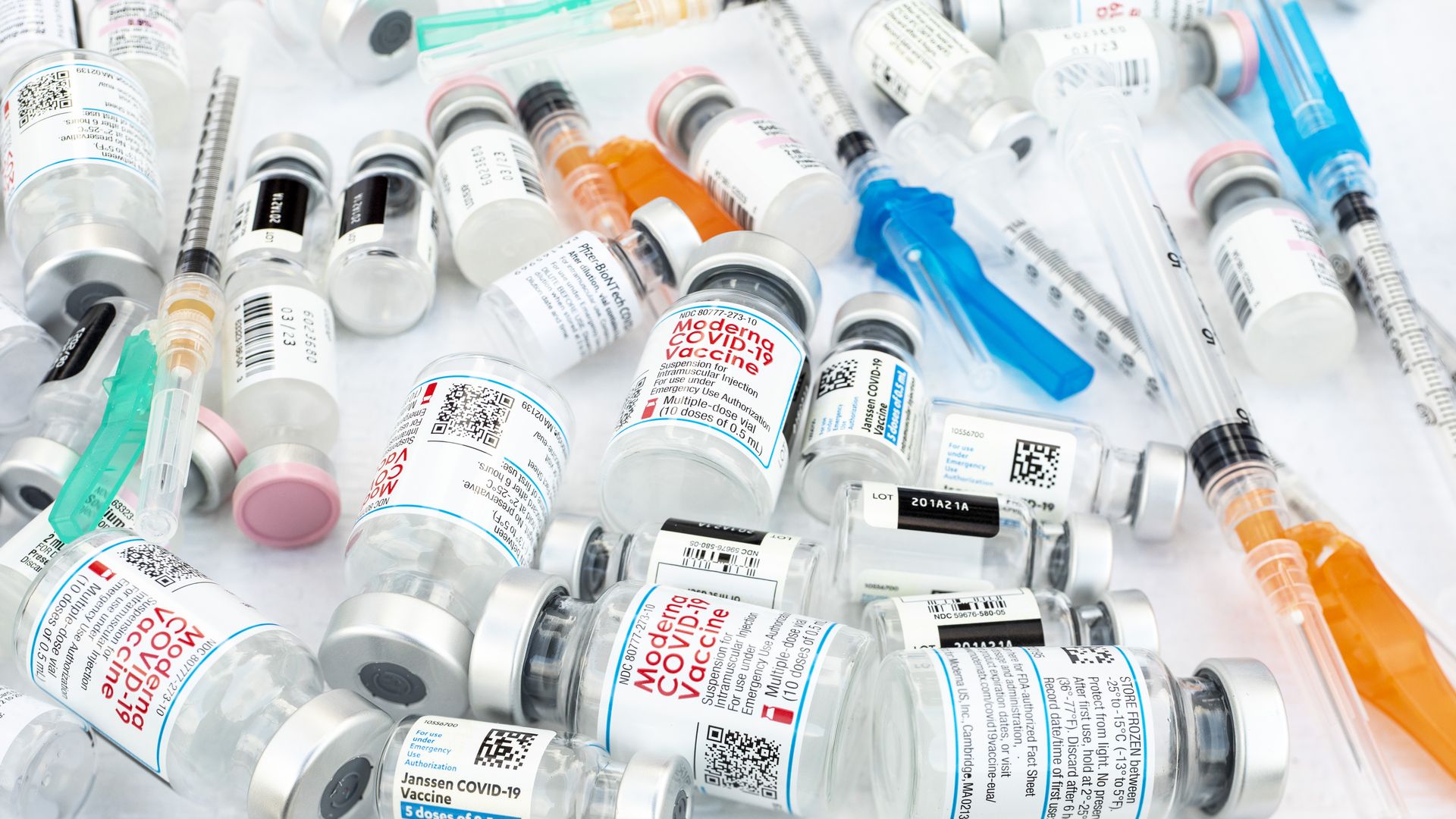 COVID-19 vaccine vials and syringes on a table.