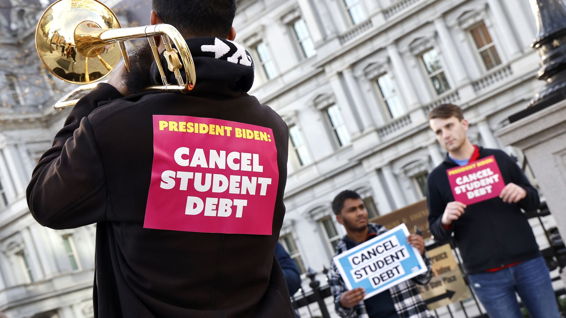 Picture of people holding signs that call on Biden to cancel student debt