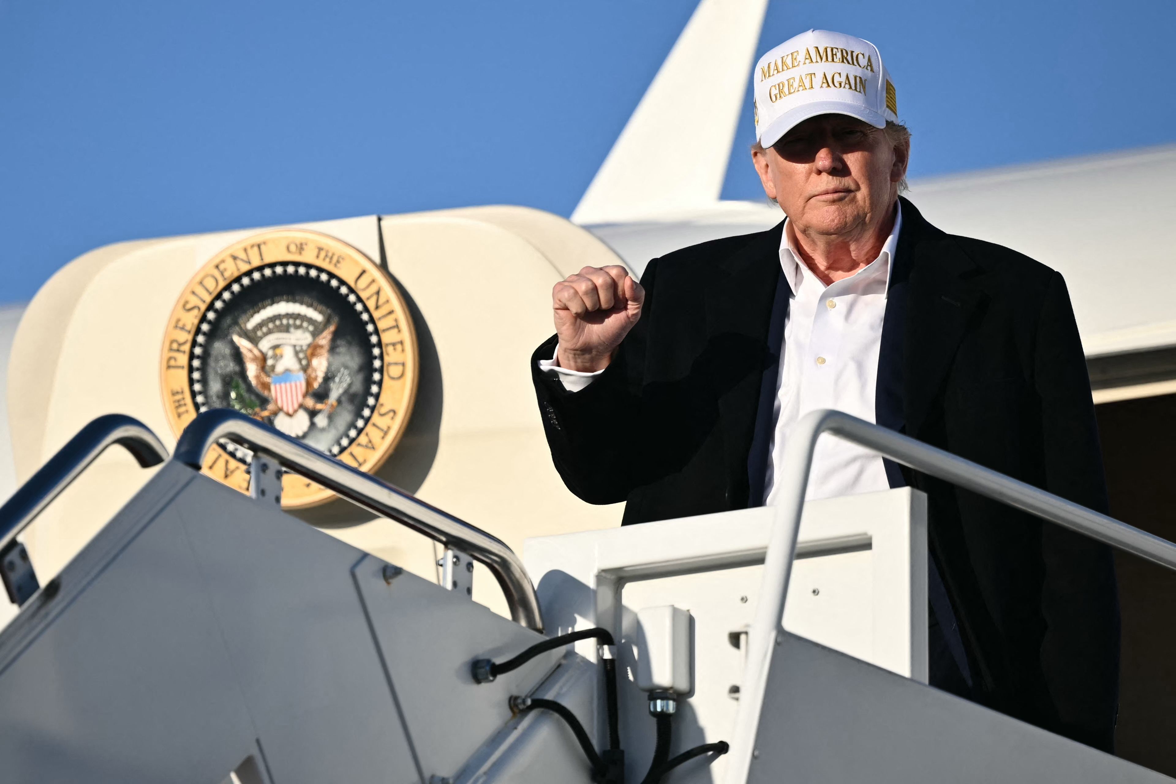US President Donald Trump raises a fist as he steps off Air Force One upon arrival at Joint Base Andrews in Maryland on April 27, 2025. Trump is returning to Washington after attending the funeral of Pope Francis and spending part of the weekend at his Bedminster resort. (Photo by Mandel NGAN / AFP)