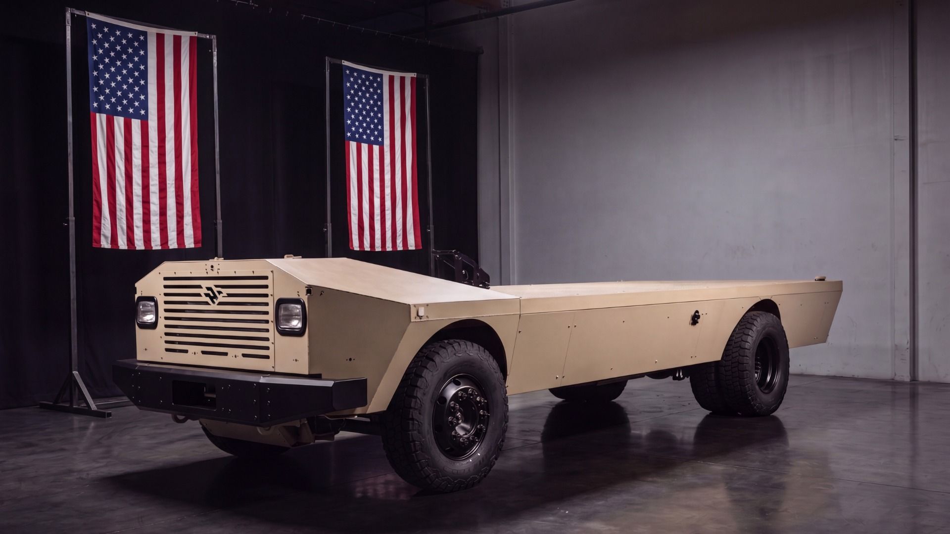 Beige military vehicle with large off-road tires on a showroom floor.