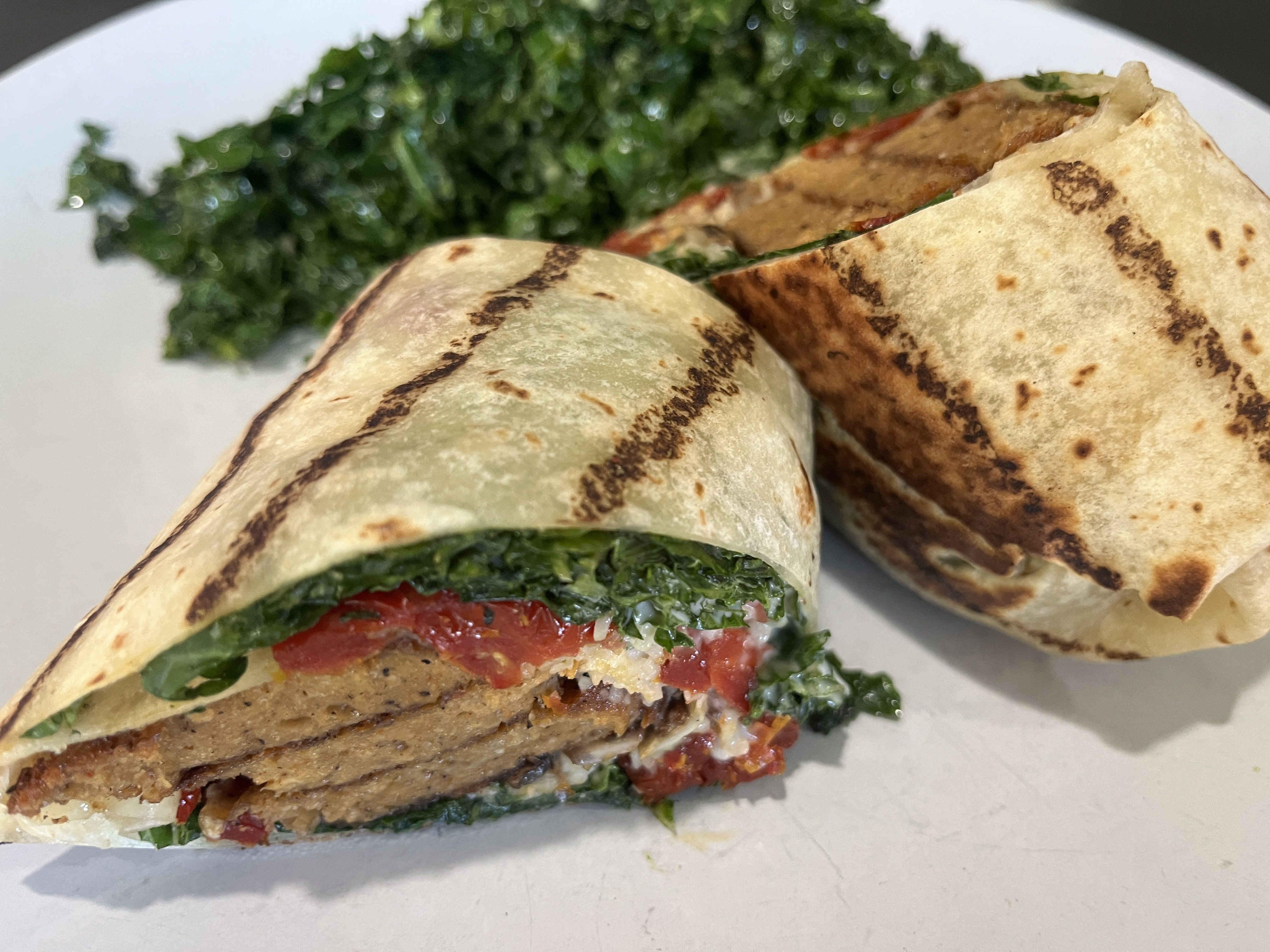 Flour tortilla with seitan slices, tomatoes and kale.