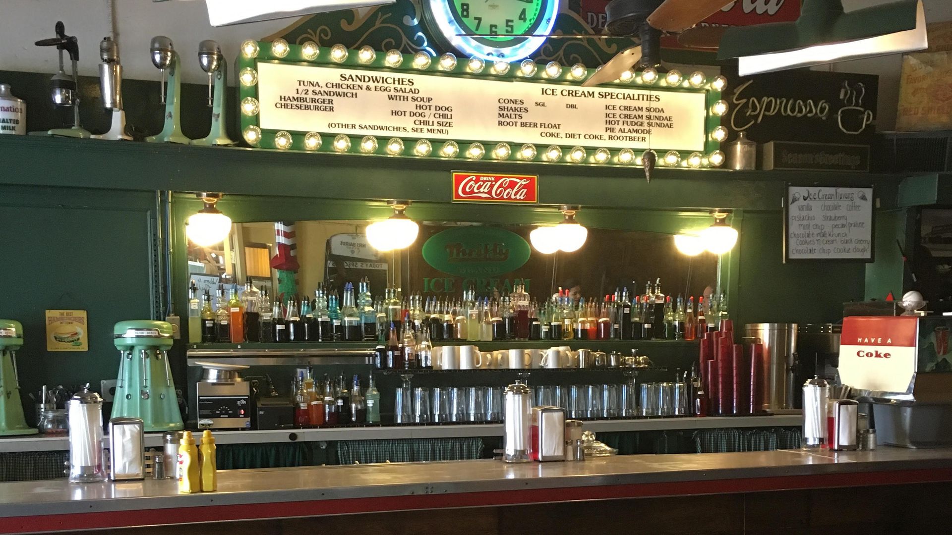 A diner counter with soda bottles on shelves behind it.