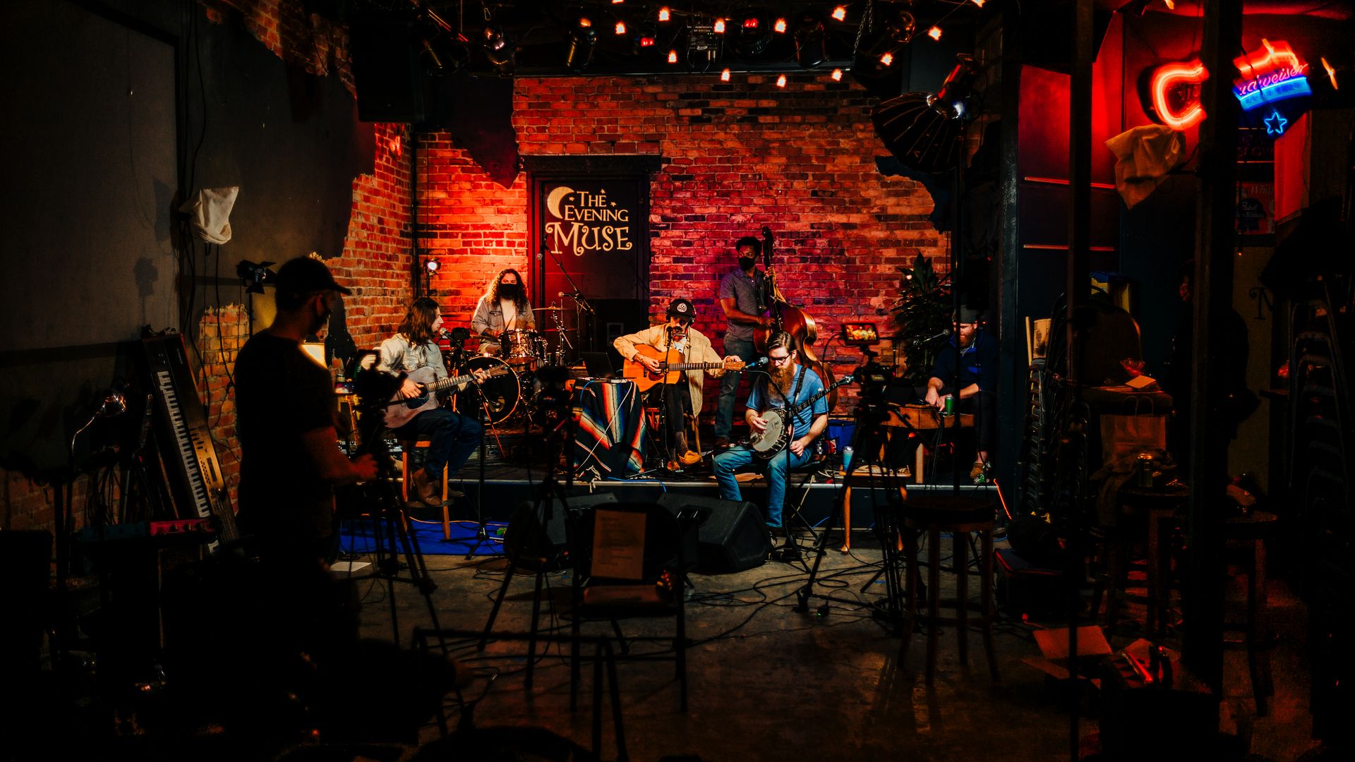 the five-person band Time Sawyer sits on stage at the Evening Muse against a redbrick wall