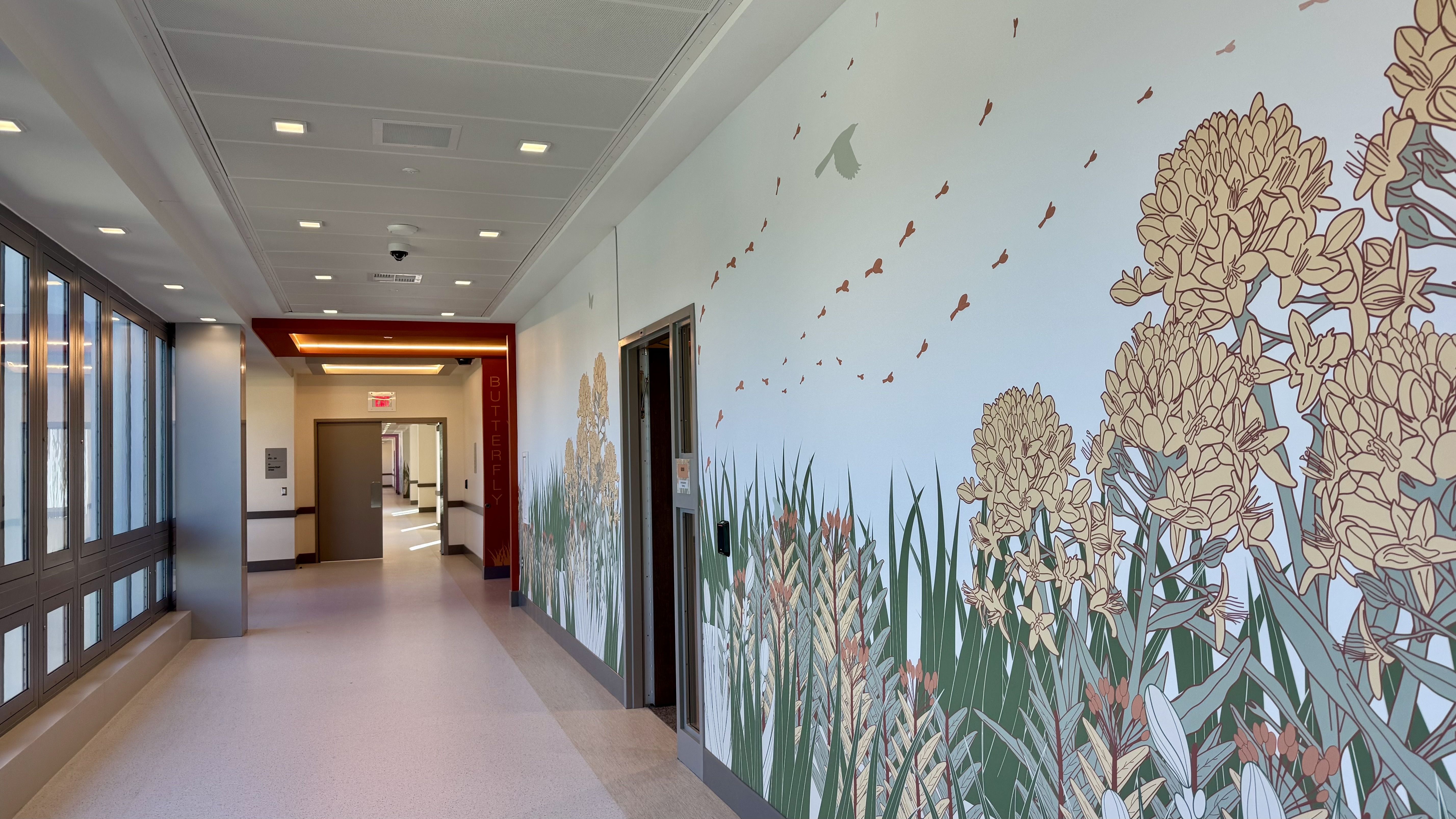 A hallway with red and pink accents and wallpaper of flowers and birds and grass