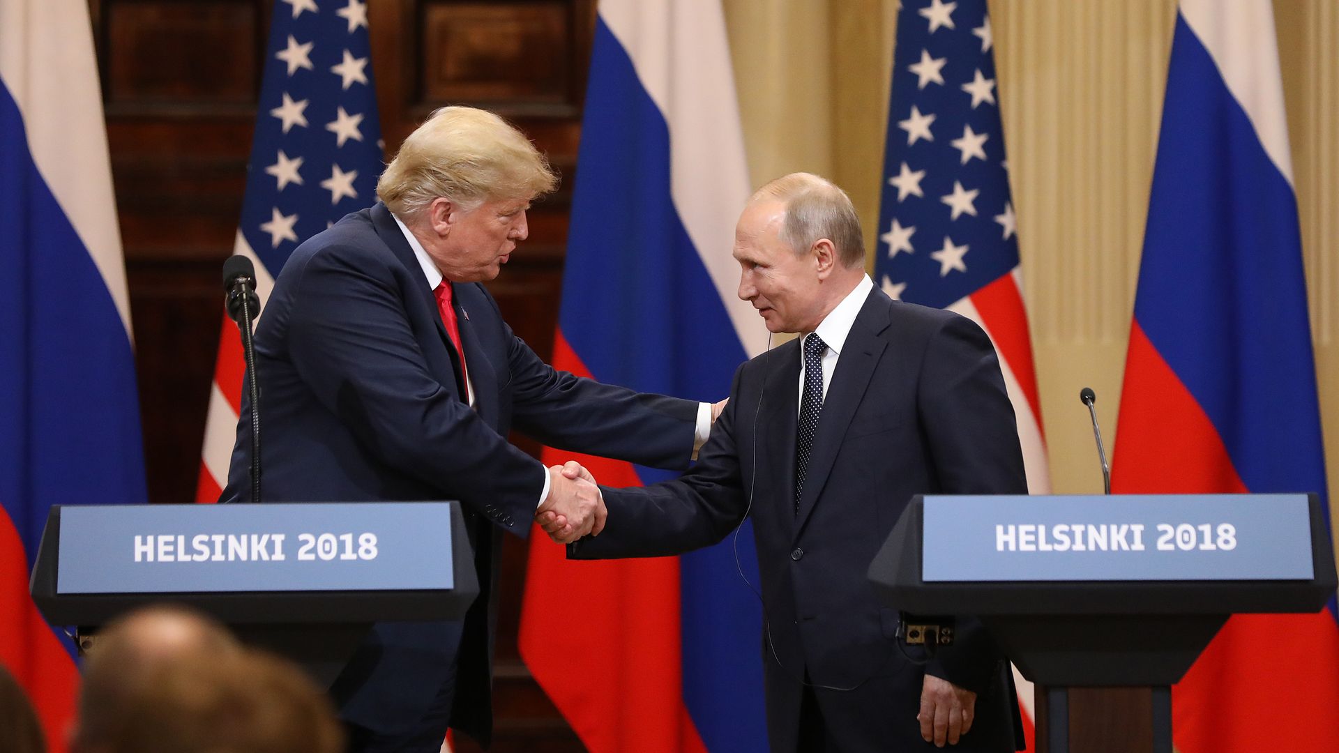 Photo of Donald Trump and Vladimir Putin shaking hands on a stage in front of people