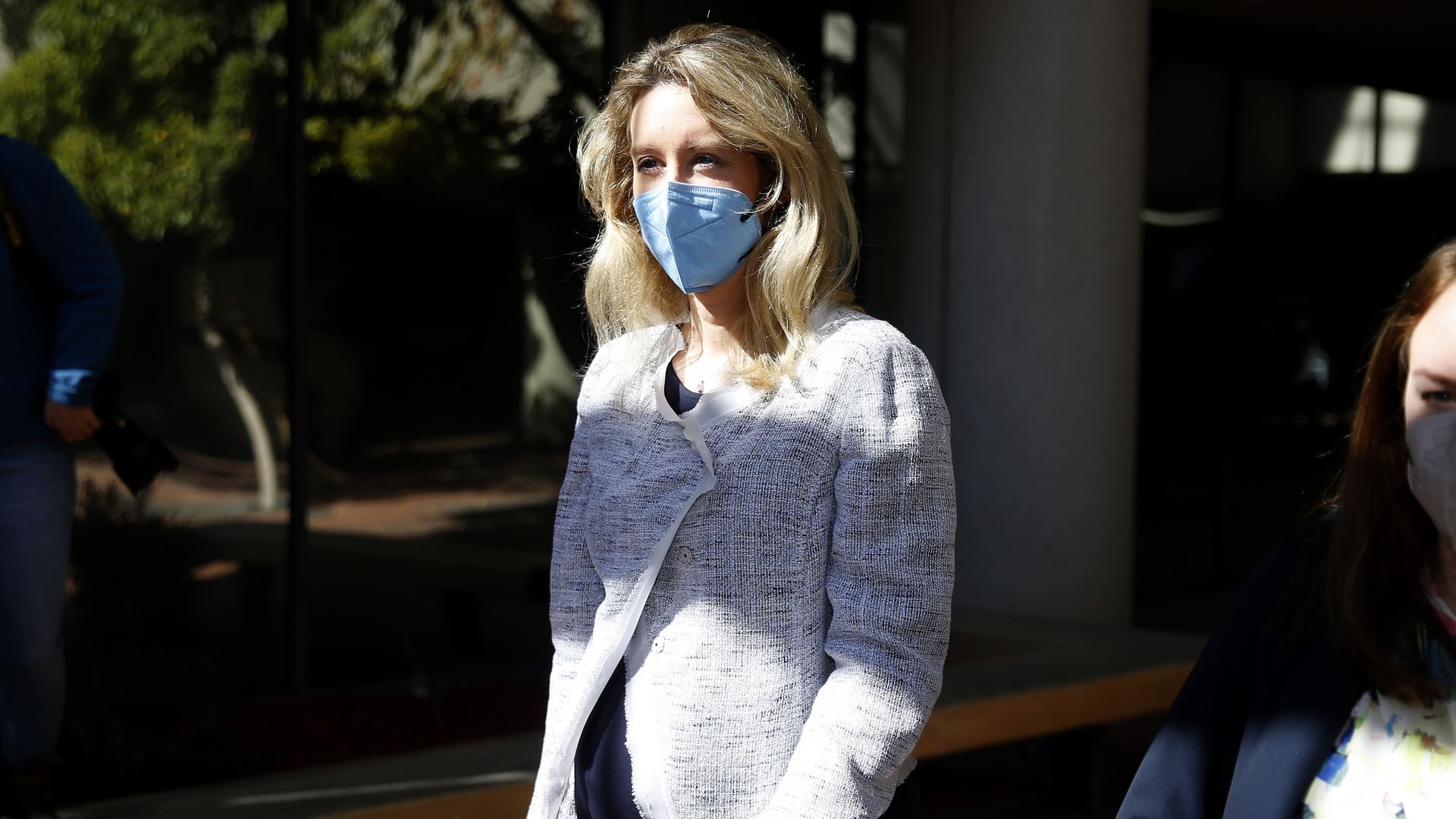 Theranos founder Elizabeth Holmes walking outside wearing a mask