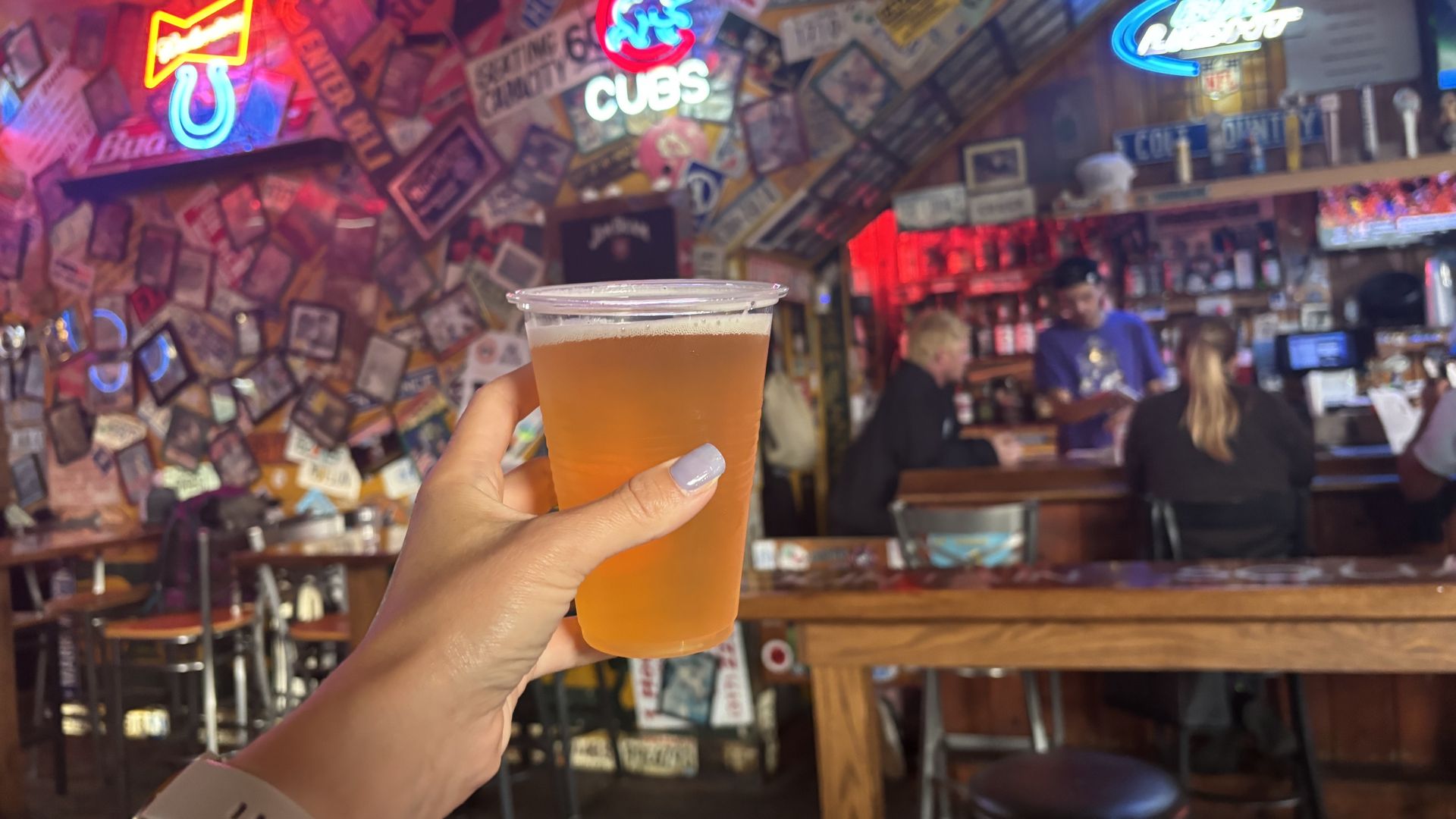 A hand holding a beer in front of a bar