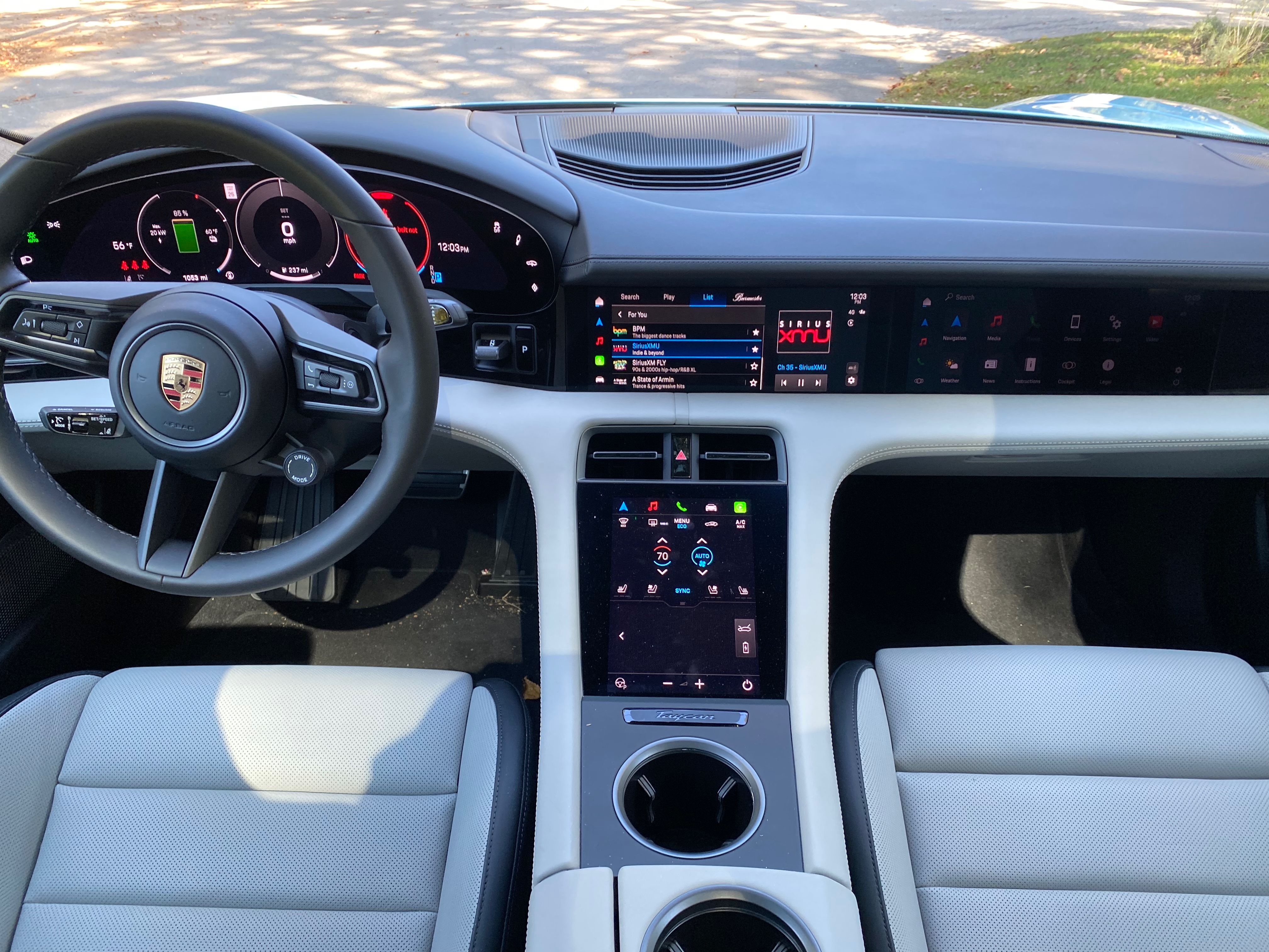 The interior of the Porsche Taycan EV, featuring white leather seats and black steering wheel.