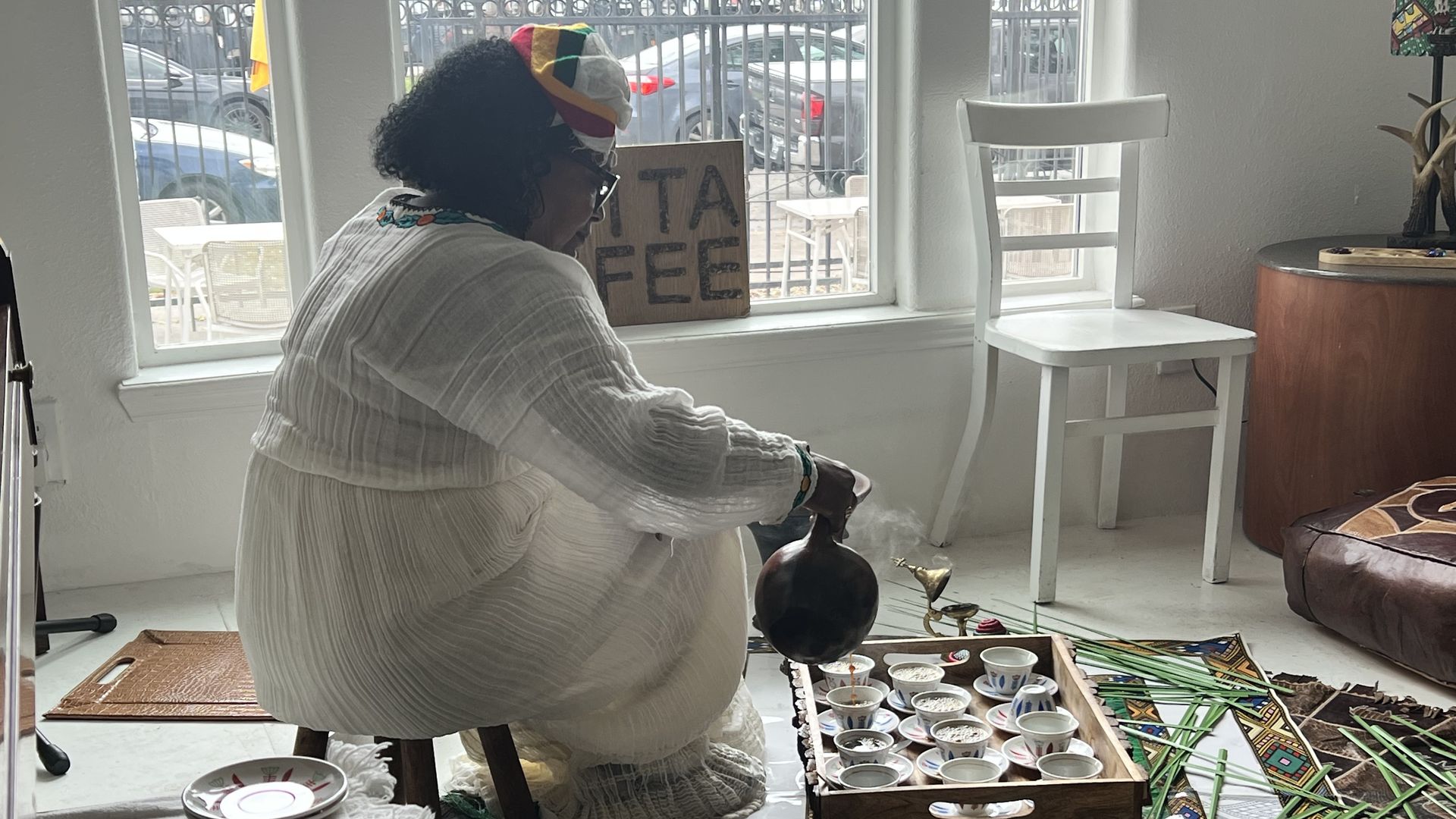 Photo of a woman in white dress pouring coffee. 