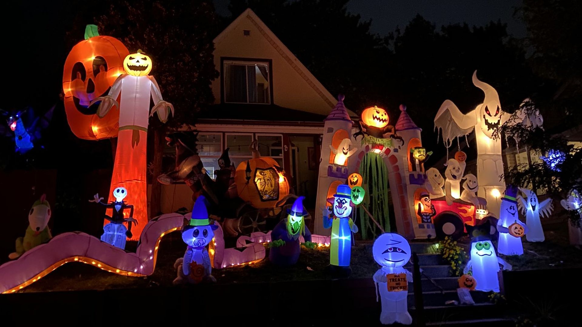 house at night covered in light up Halloween inflatable decorations