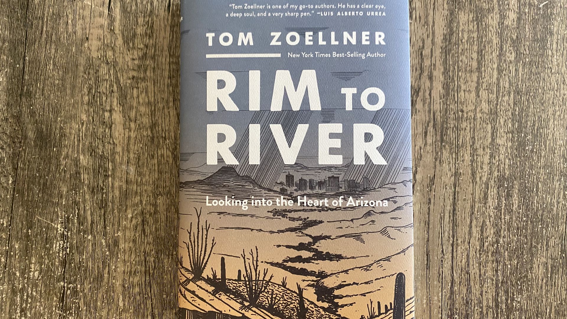A hardcover book titled Rim To River on a gray wood-grained surface.