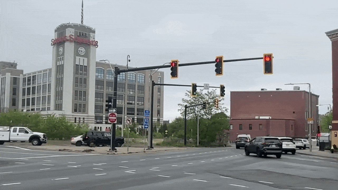 Cars drive around the Sullivan Square rotary in Charlestown and a pedestrian runs across multiple lanes when traffic dies down.