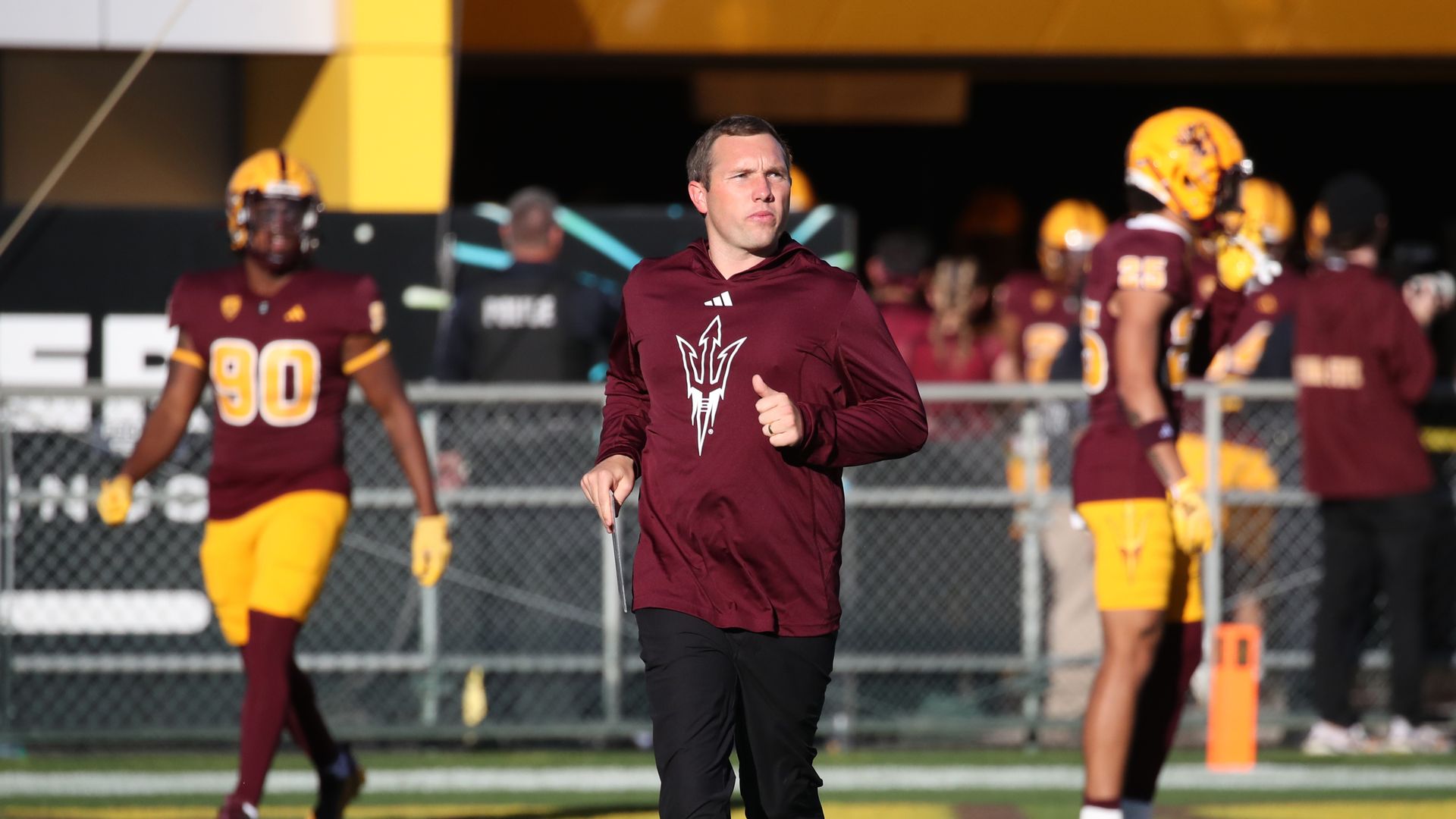 A coach running onto a football field. 