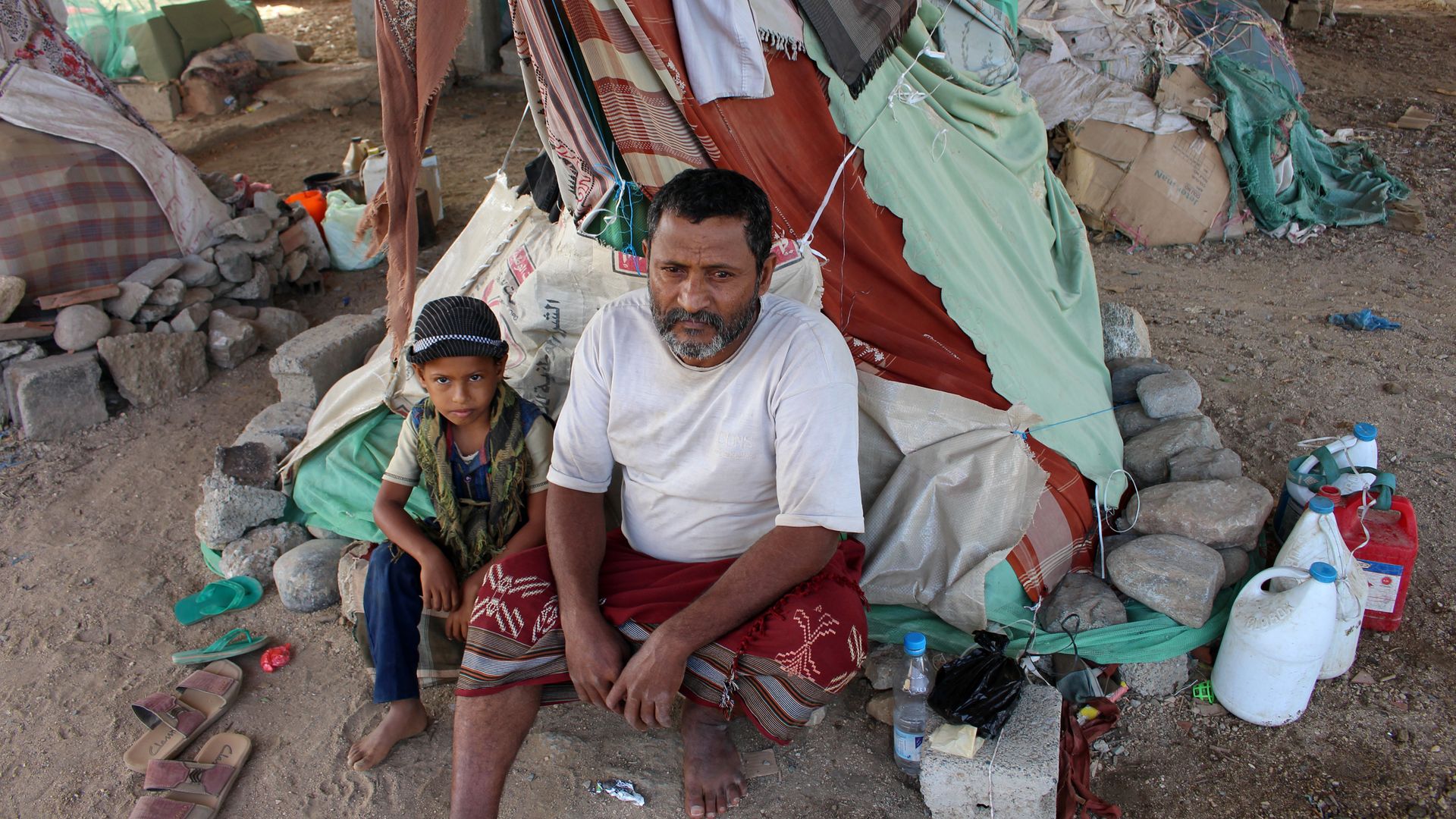 Displaced Yemenis sit under a makeshift shelter at a camp for internally displaced persons.