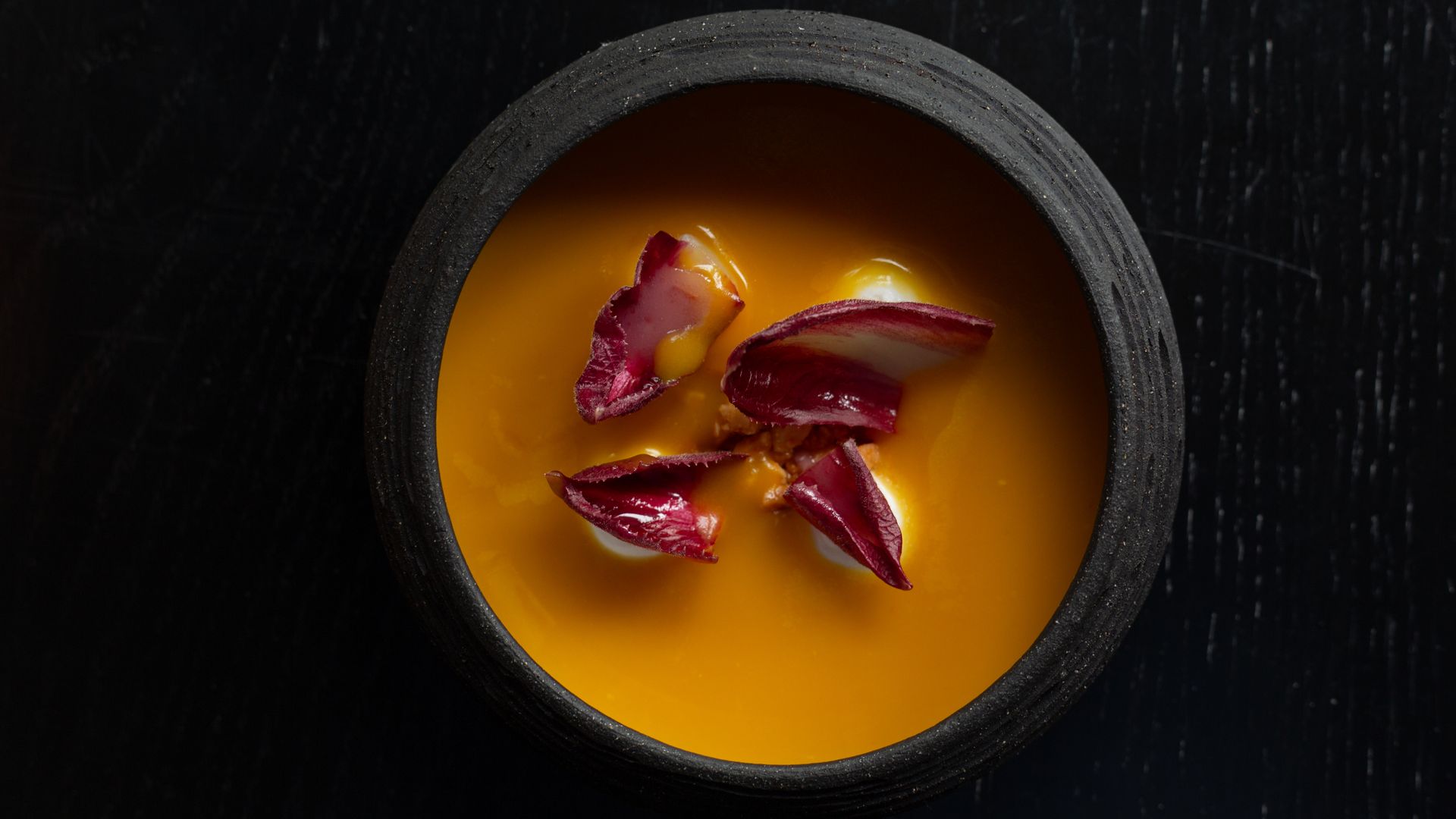 orange soup in a black bowl