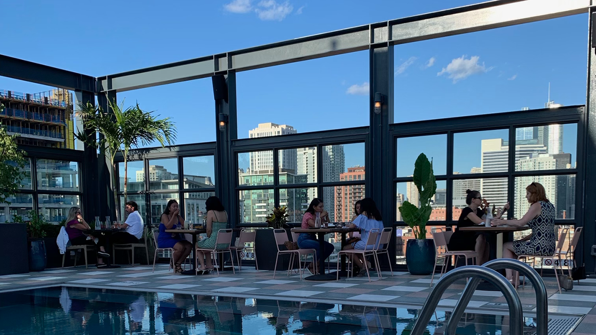 People dine at a rooftop restaurant with a pool