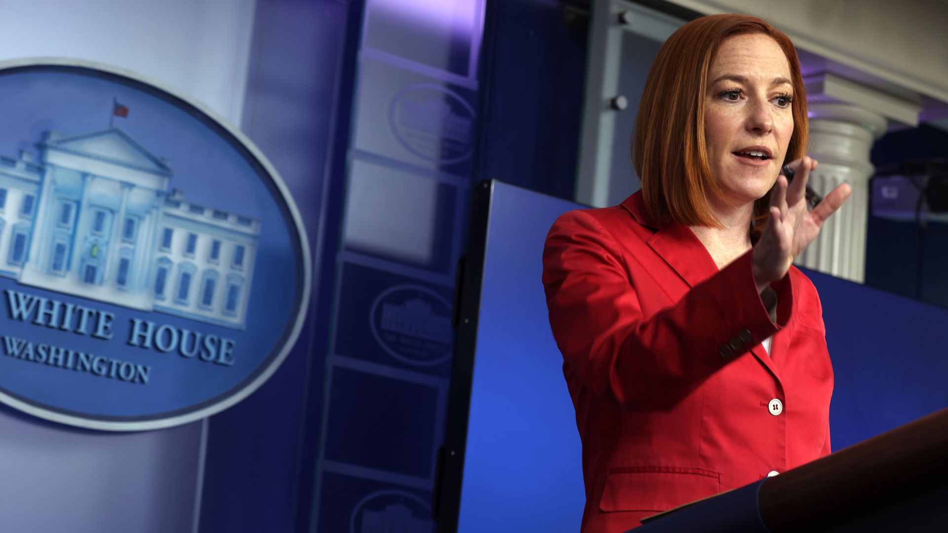 Jen Psaki stands at the White House briefing podium 