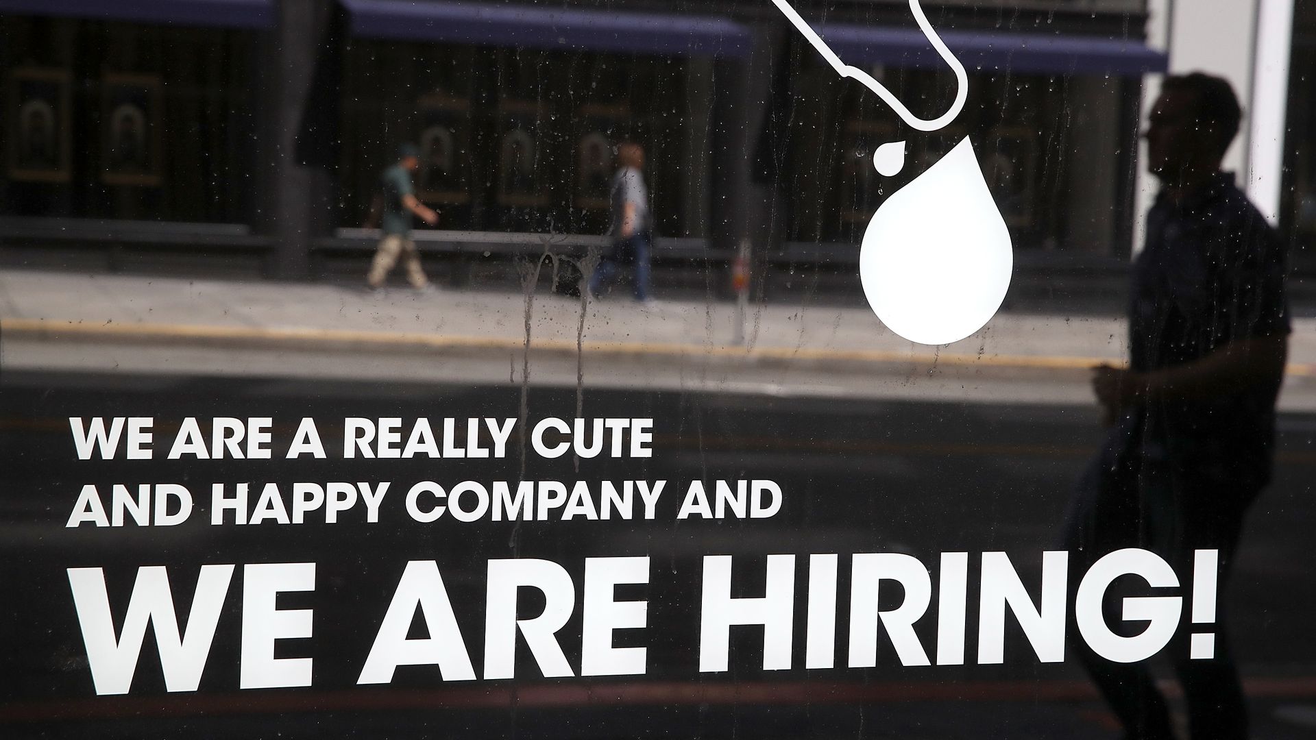 A "We Are Hiring" sign on a window