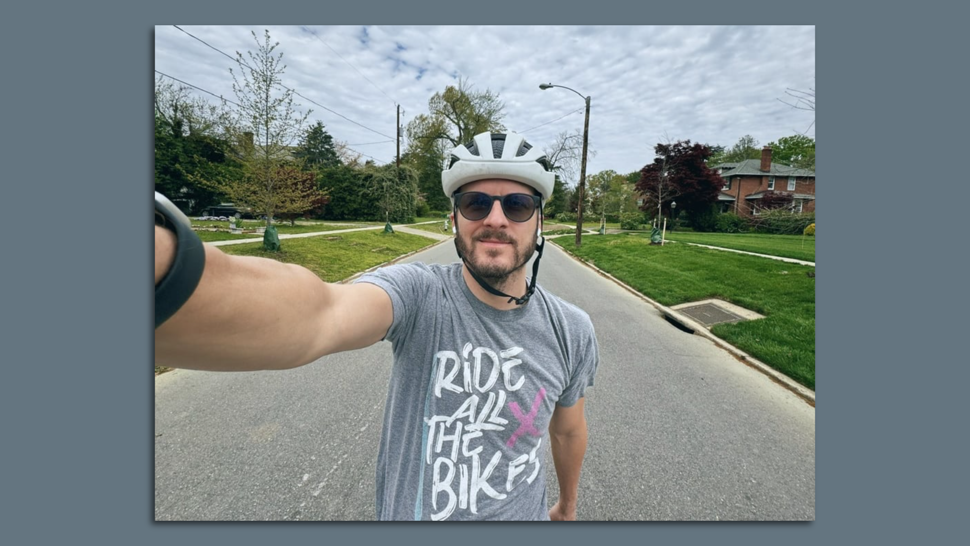 A man in a bike helmet wearing a shirt that says Ride all the bikes 