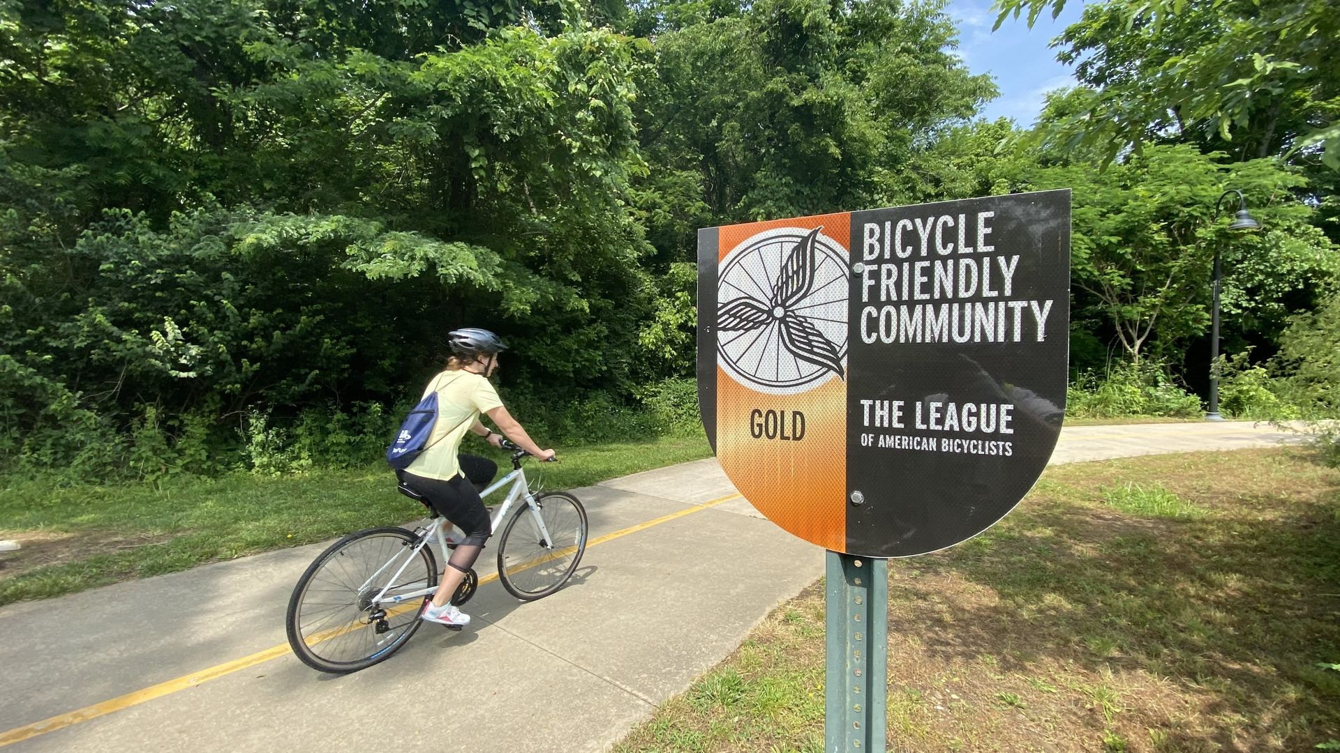 A cyclist rides by a sign that reads: Bicycle Friendly Community.