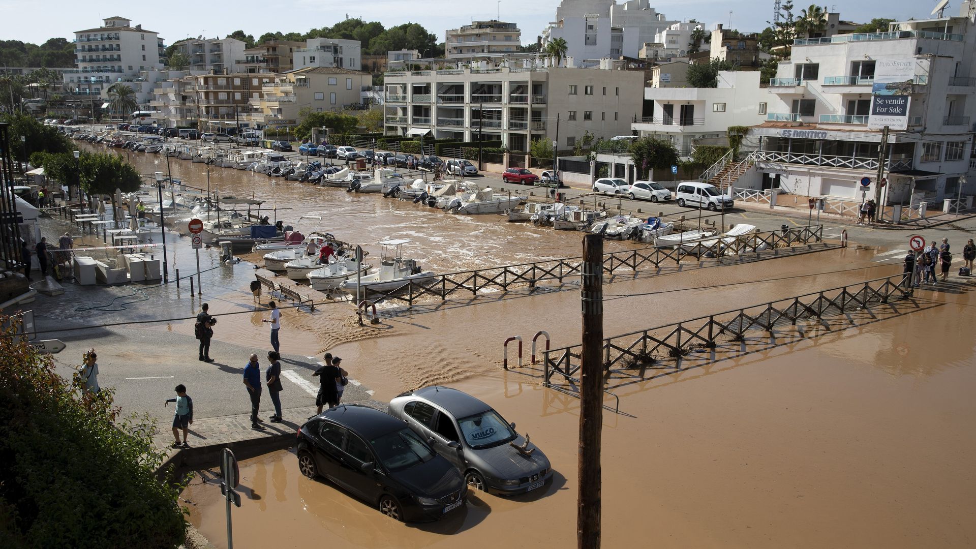 People watch the damaged area near the port of Porto Cristo after heavy rainfall hit the area