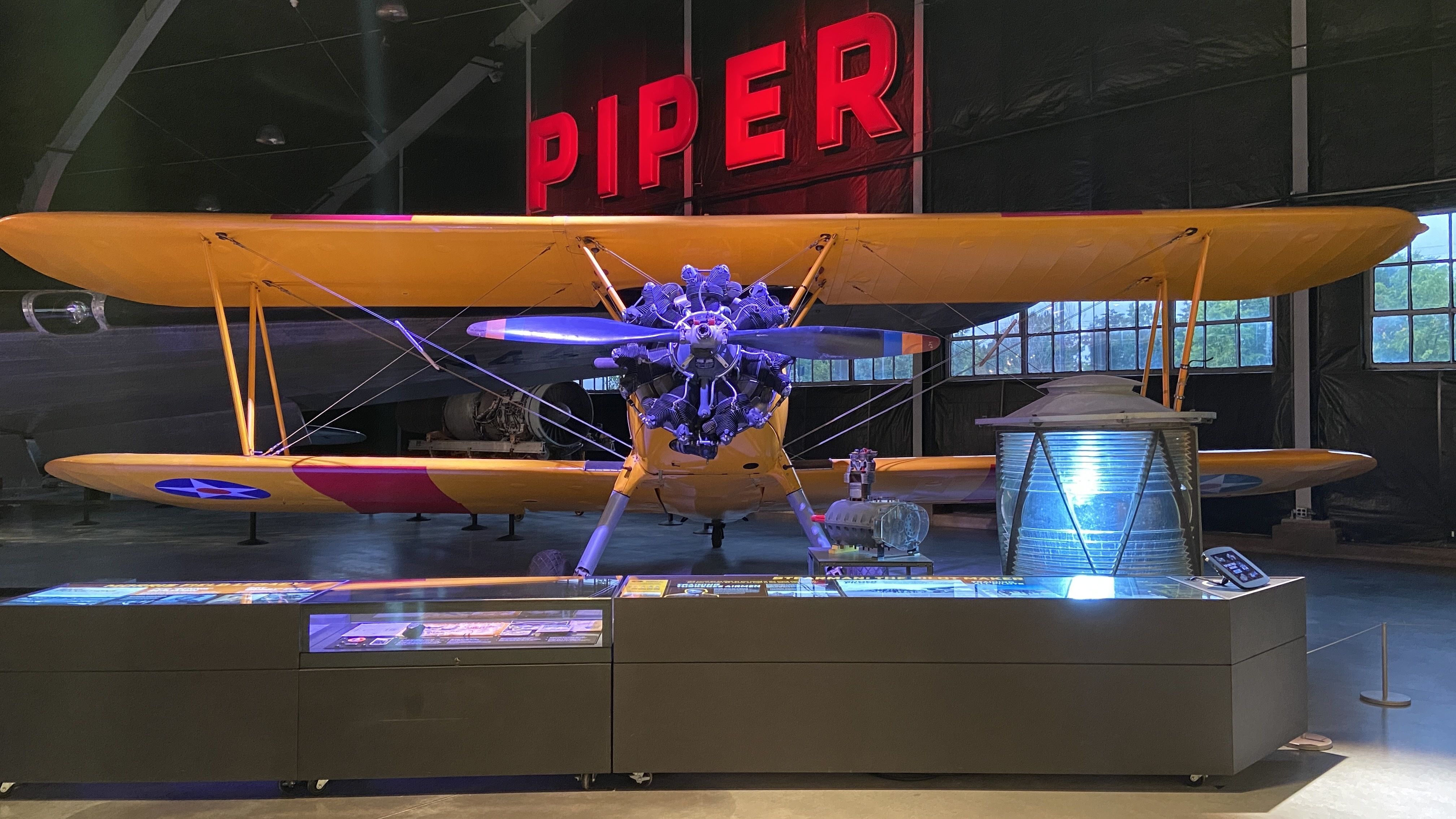 A plane with the word "PIPER" in lit up red letters behind it.