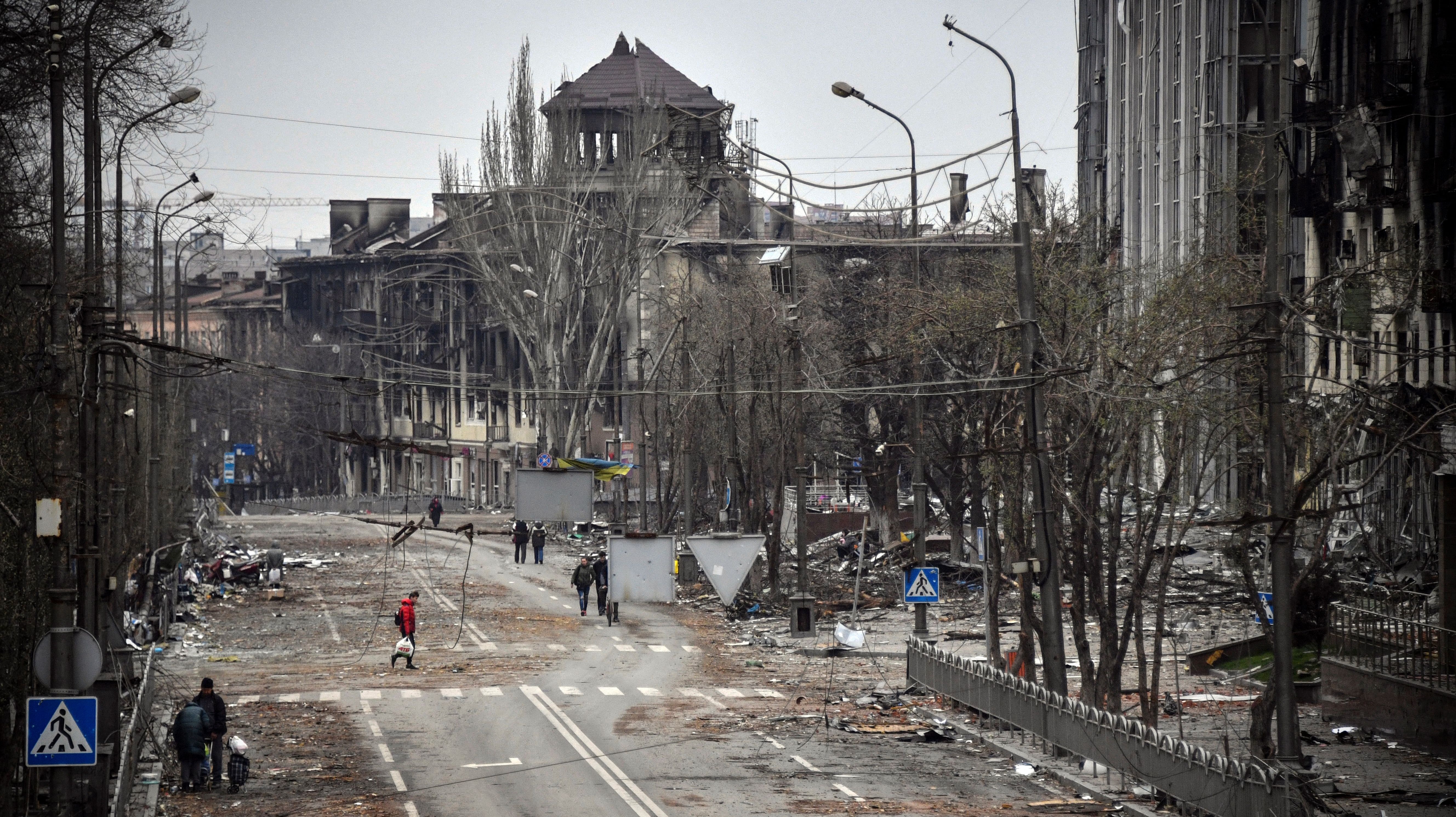 People walk down an avenue of Mariupol on April 12, 2022, as Russian troops intensify a campaign to take the strategic port city.