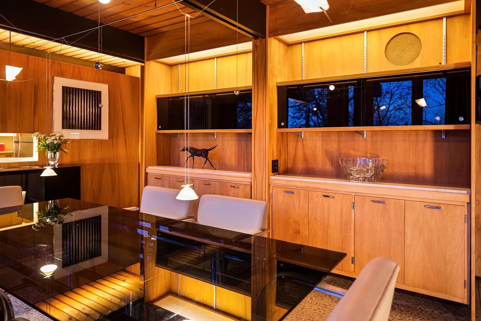 A dining room with a black table and wood cabinets.