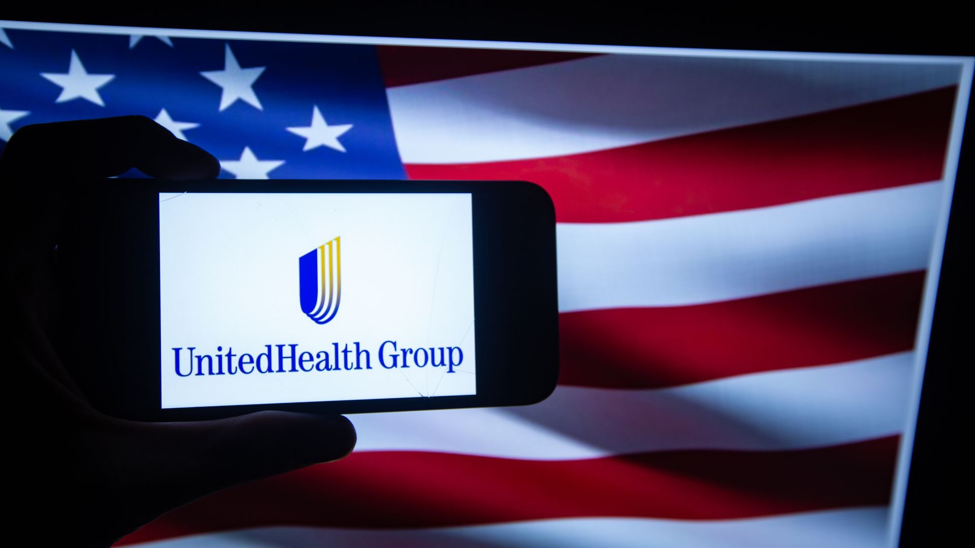 MAn holding phone that has united health group logo on it