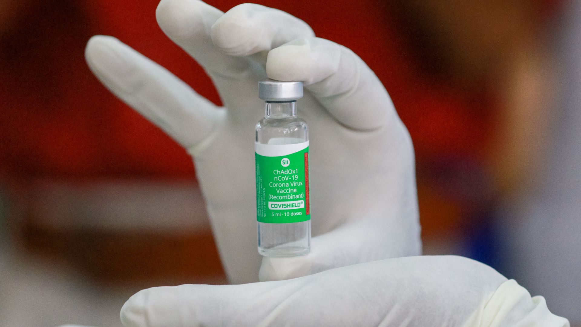 Picture of hands holding an AstraZeneca vial