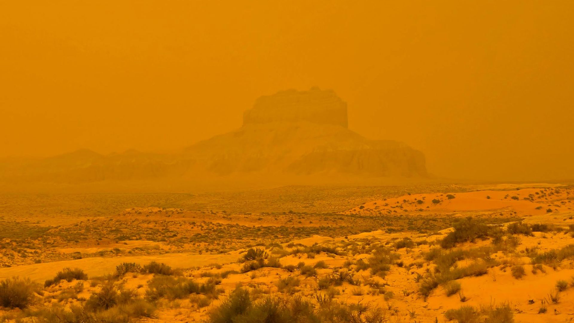 A rocky bluff obscured by orange smoke