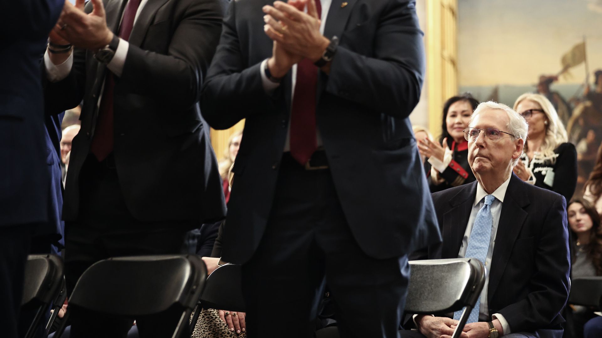 Sen. Mitch McConnell sits during Trump's inauguration while others around him stand and clap.