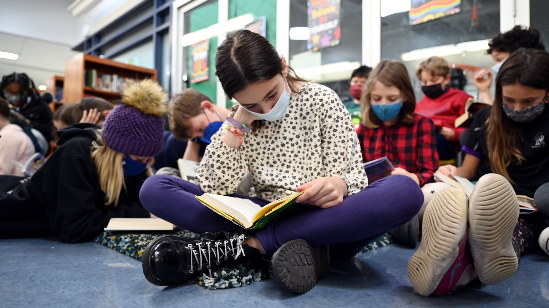 Sophia Koutroulos, 10, front, and 5th graders are reading books at the library of Bromwell Elementary School in Denver, Colorado.