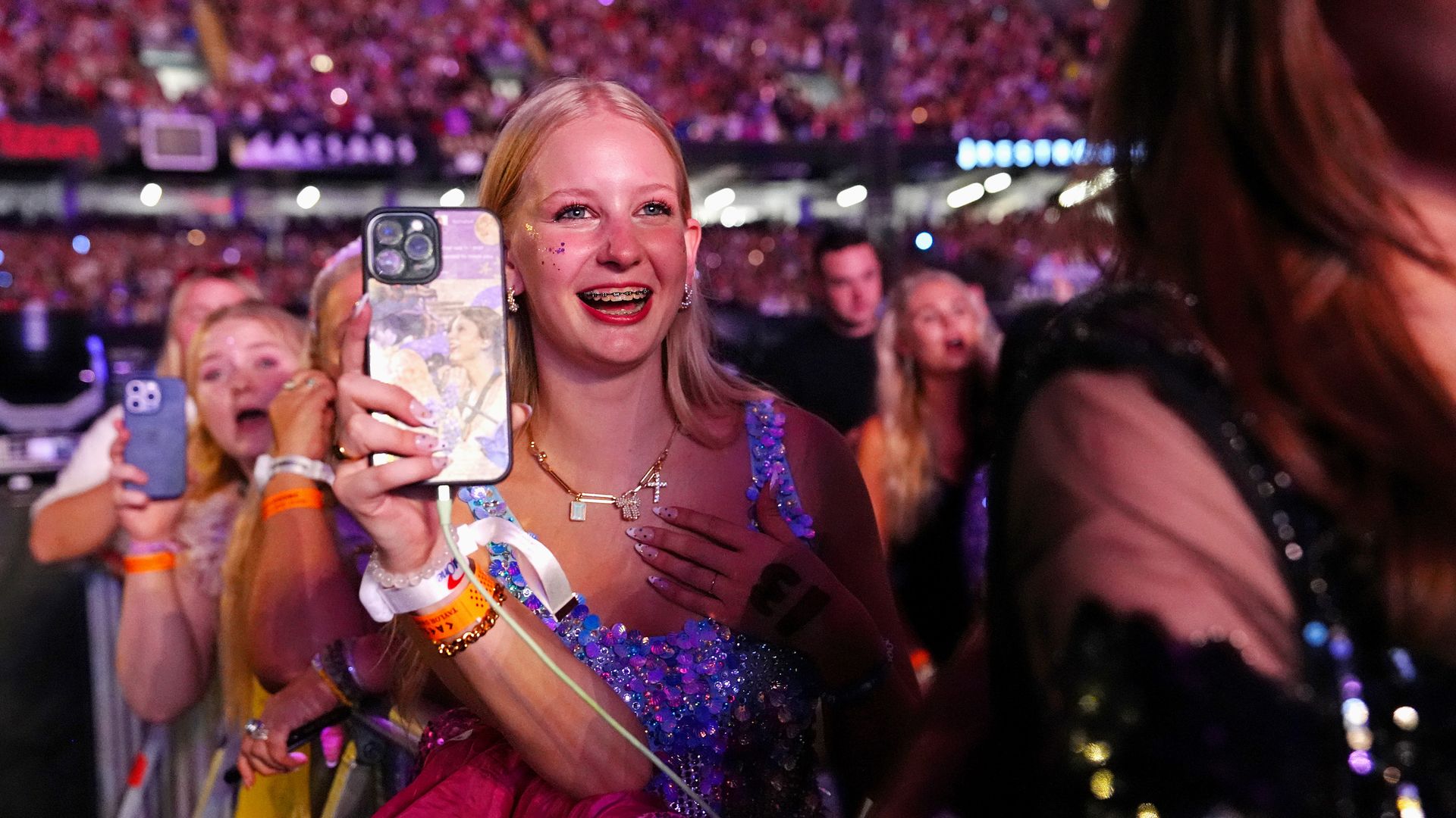 A young woman uses her phone to film something happening behind the photographer during a concert in the Superdome.