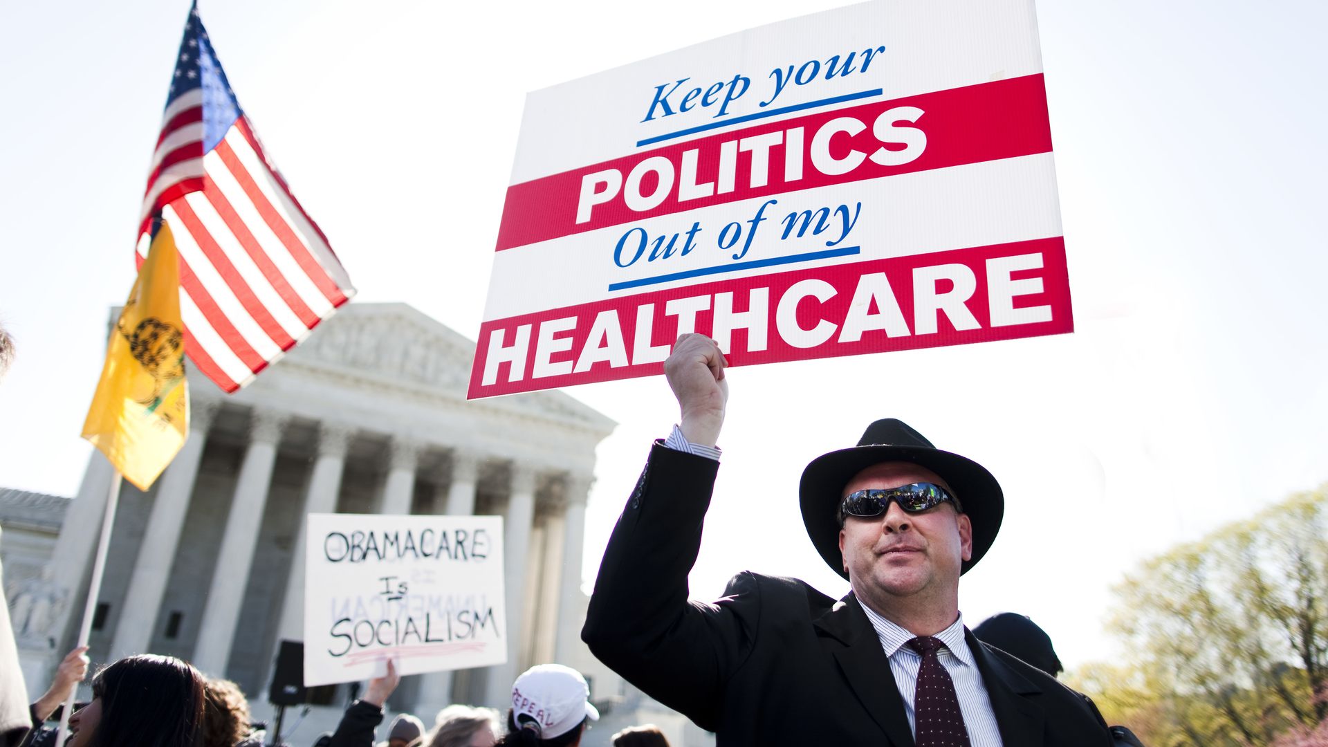 Protesters outside the Supreme Court waving signs about the ACA