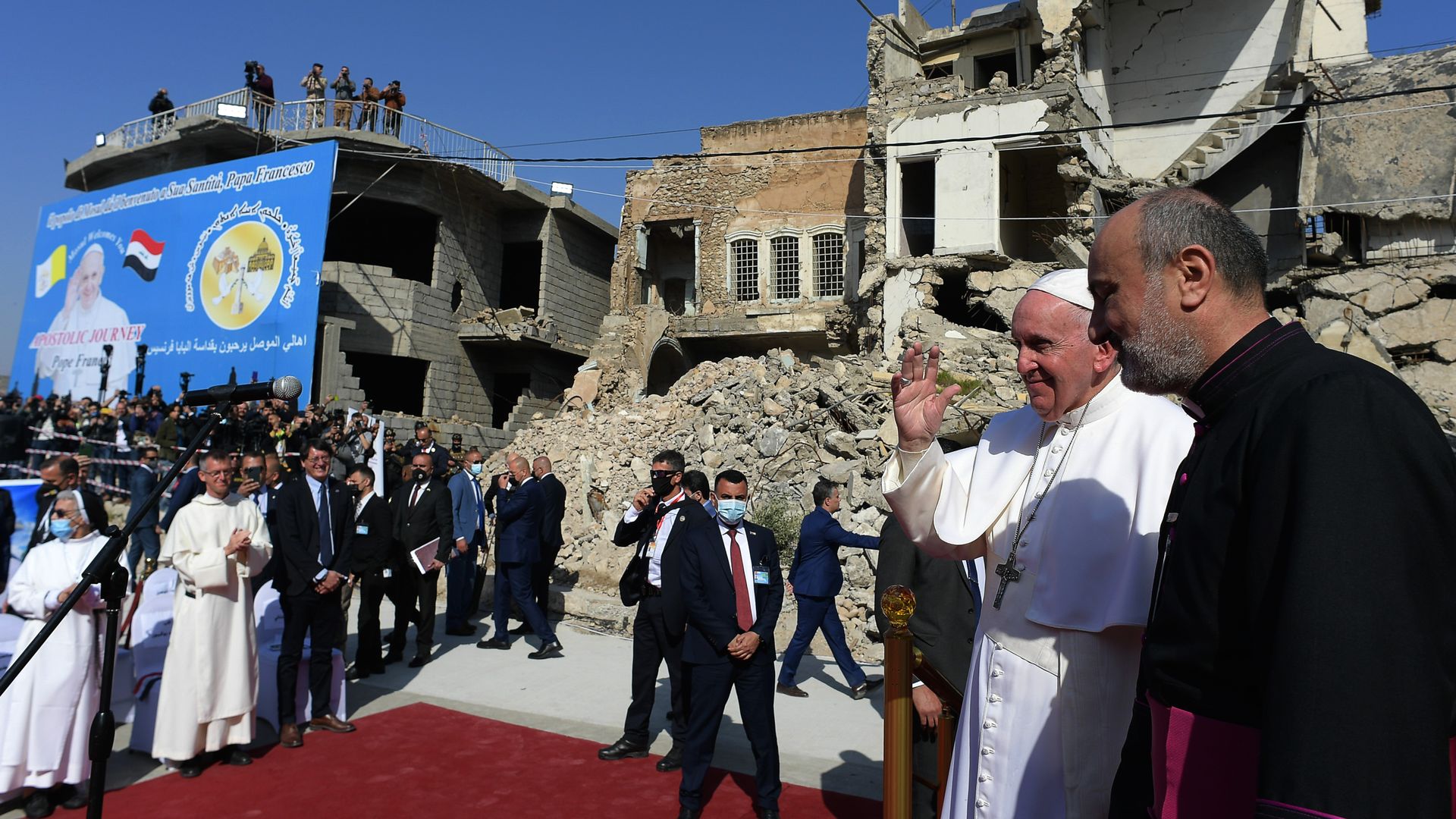  Pope Francis (C), raises his hand in greeting as he arrives at a square near the ruins of the Syriac Catholic Church of the Immaculate Conception in northern Iraq