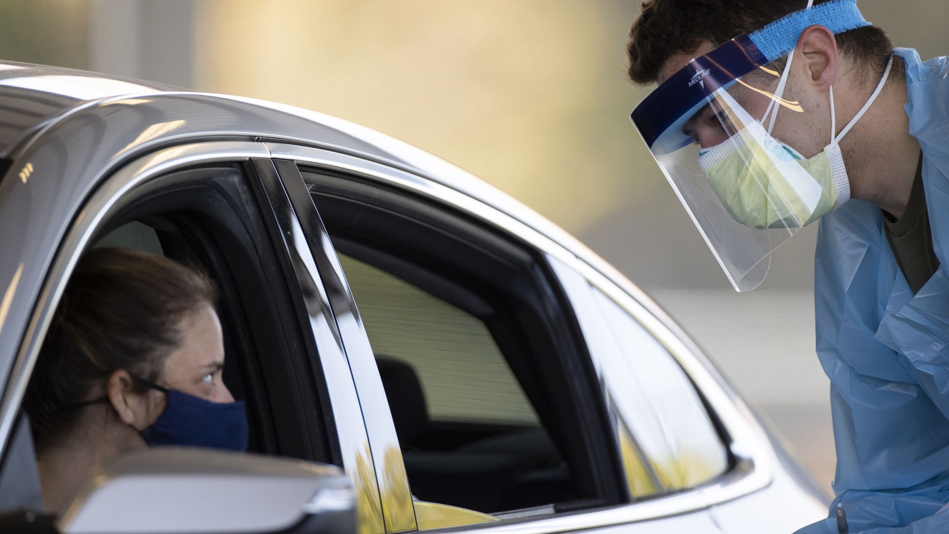 Man testing a woman for coronavirus in her car