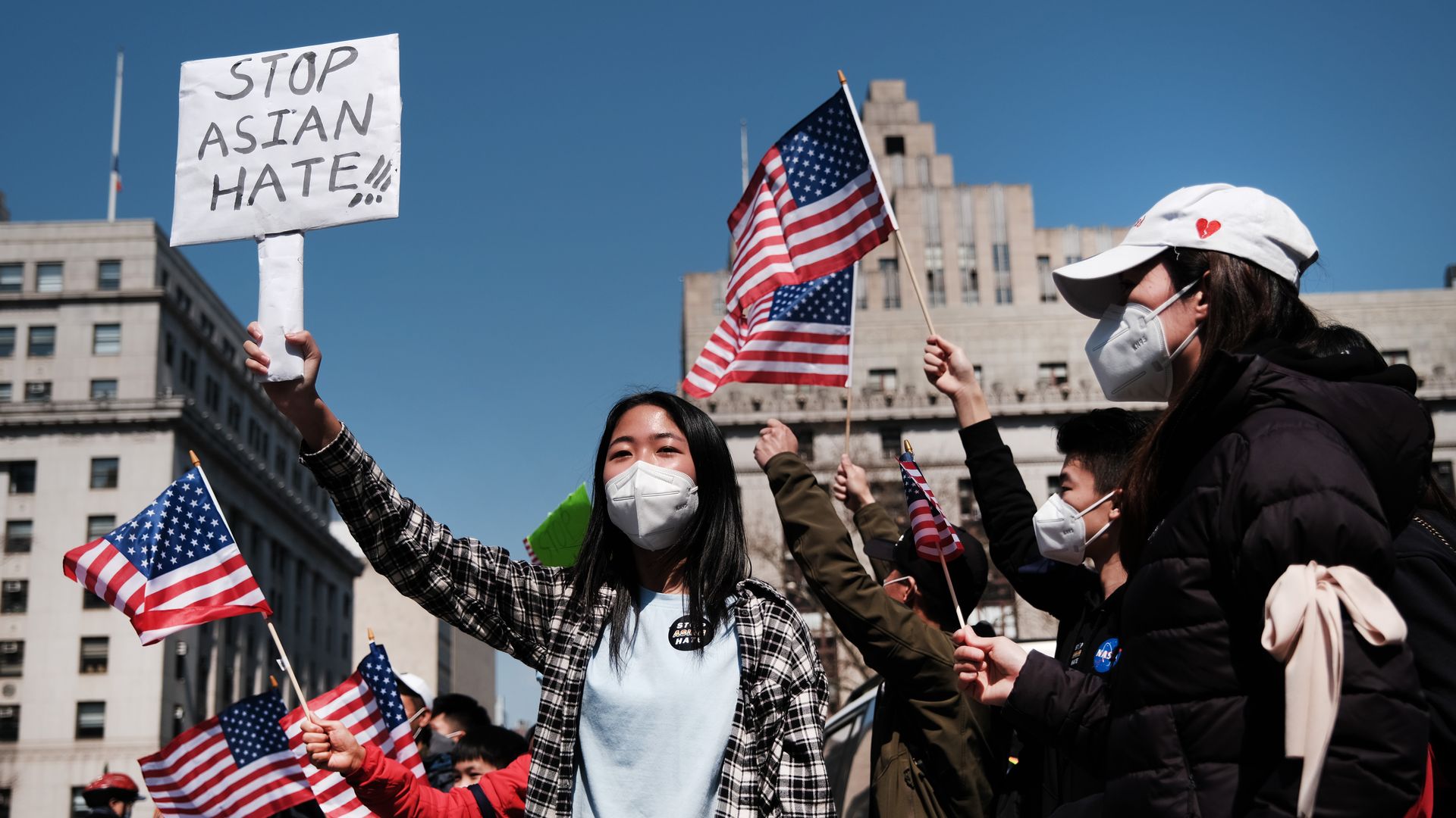 A picture of a girl holding a sign that says "STOP ASIAN HATE"